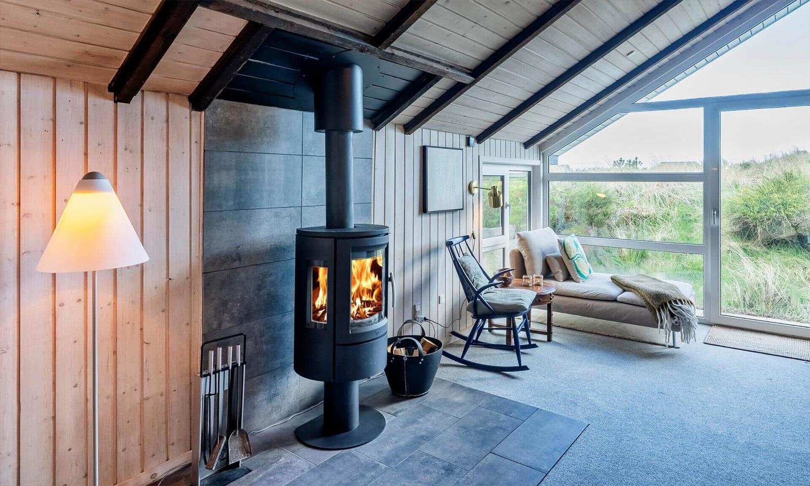 Raum mit Kamin, Sitzgelegenheit und großem Fensterblick auf Grasland.