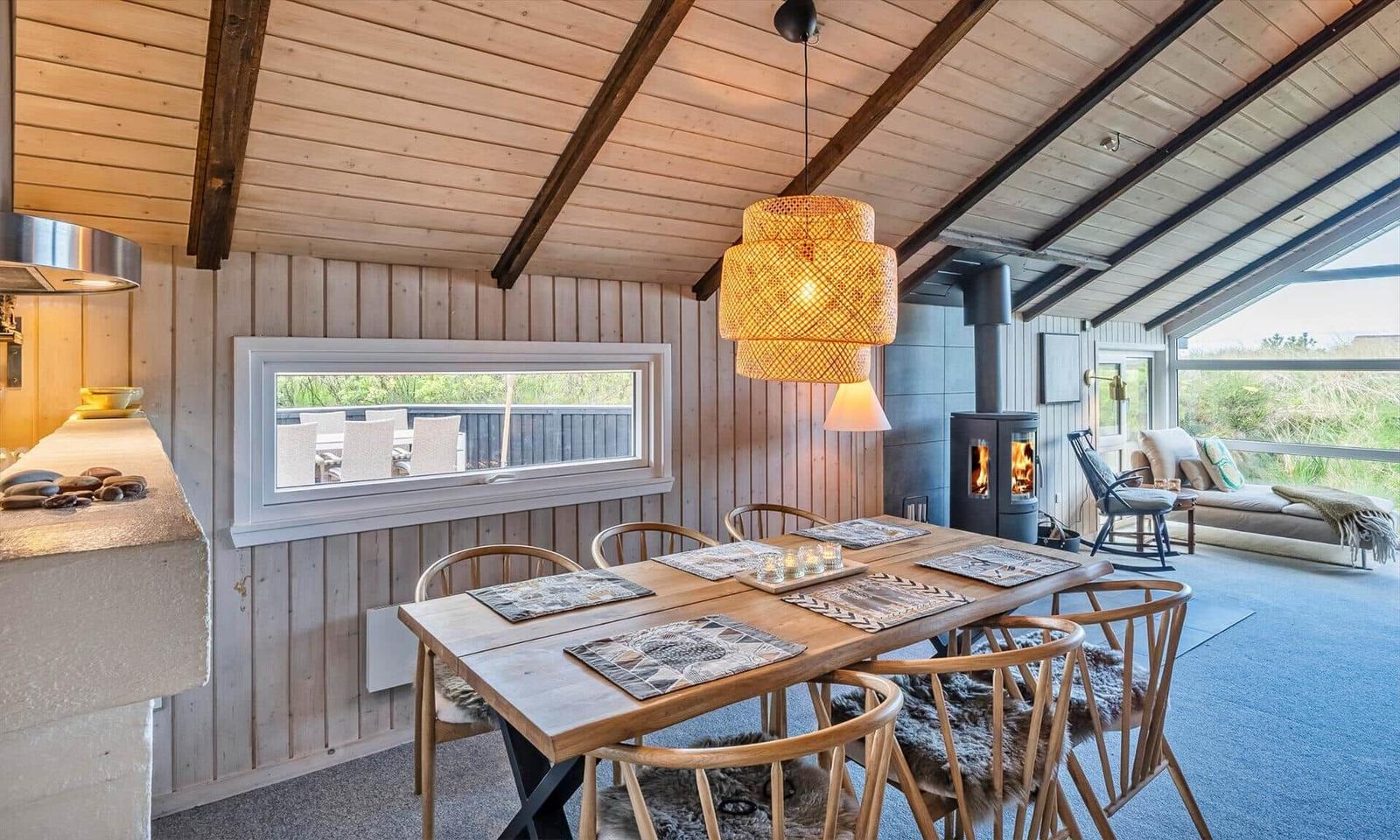 Esszimmer mit Holztisch, Stühlen und Kaminofen. Blick auf Terrasse und Garten.