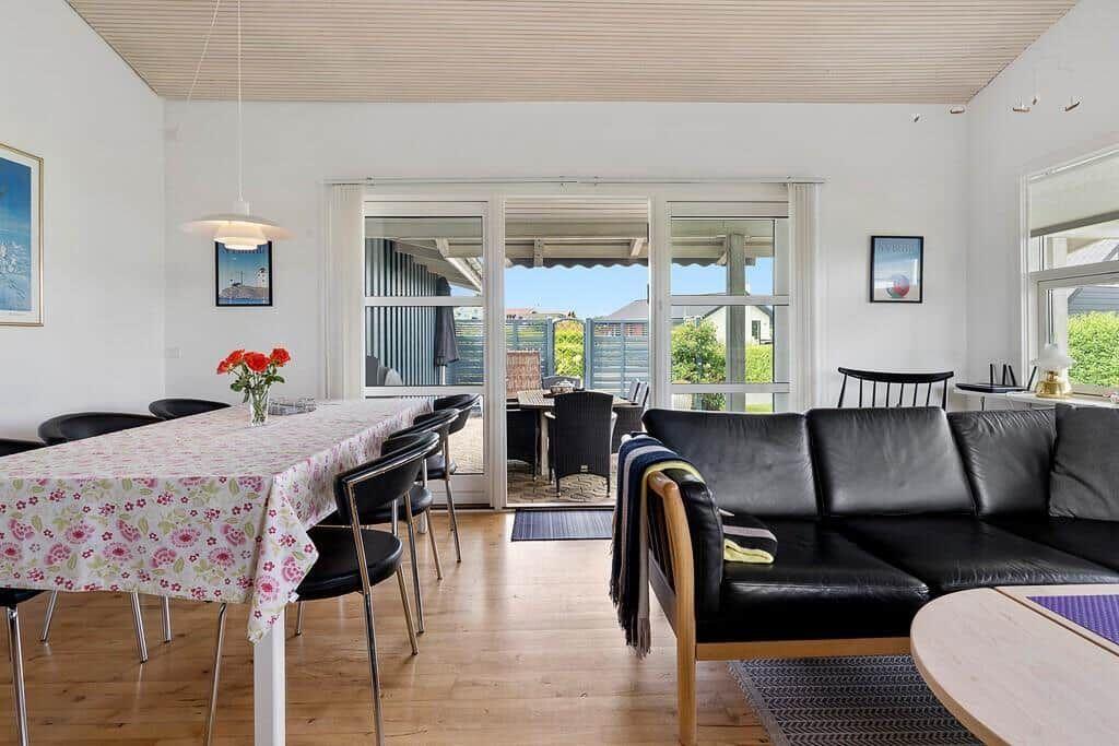Wohn- und Essbereich mit Tisch, Stühlen und Sofa. Durchgang zur Terrasse mit Blick auf Garten.