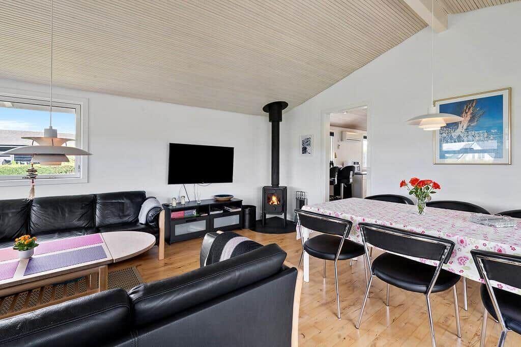 Wohn- und Essbereich mit Sofa, Esstisch, Kamin und TV.
