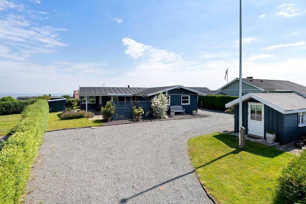 Ein blaues Ferienhaus mit Garten und Kiesweg. Blick auf das Meer.