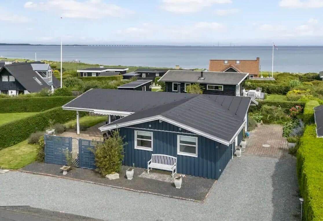 Blau gestrichenes Ferienhaus mit Garten und Blick aufs Meer.