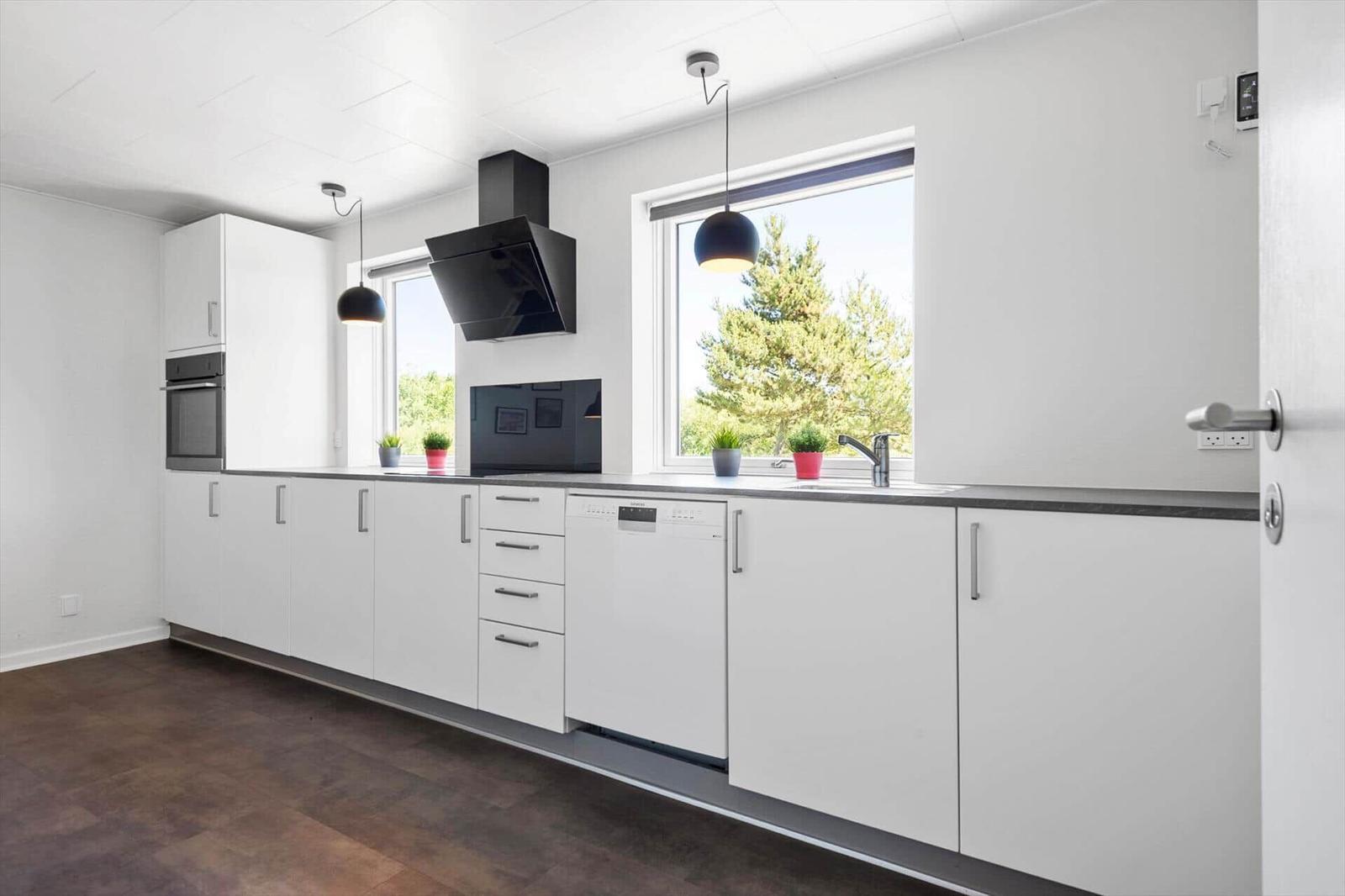 Moderne Küche mit weißen Schränken, Fenster und Küchengeräten.