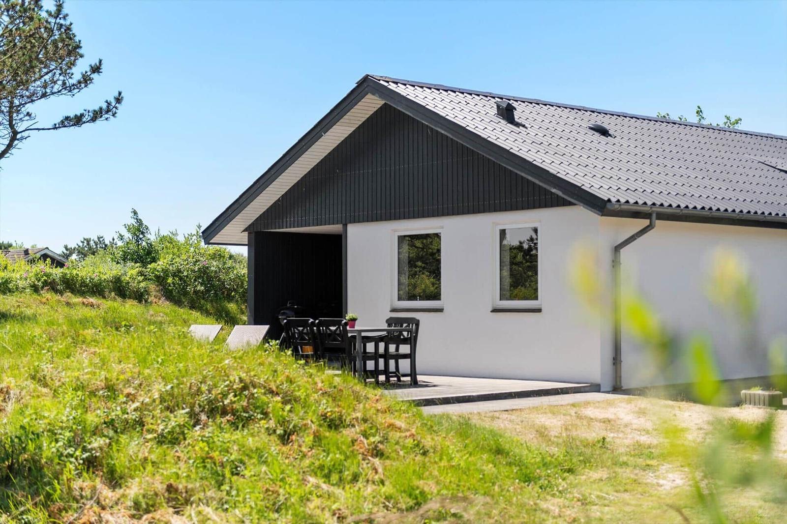 Moderne Villa mit Terrasse und Garten. Schwarz-weißes Design unter blauem Himmel.