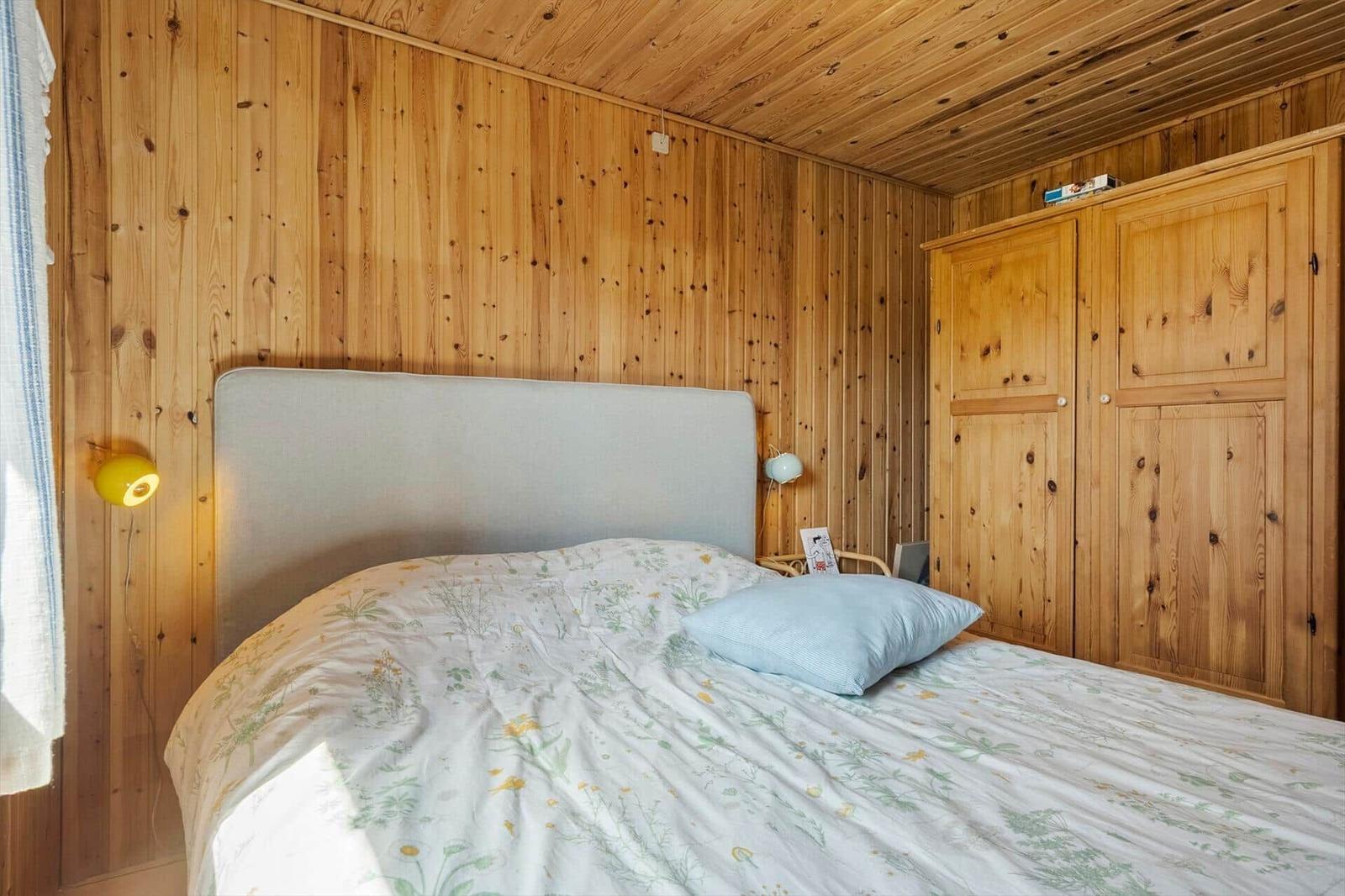 Schlafzimmer mit Holzwand, Bett und Kleiderschrank.