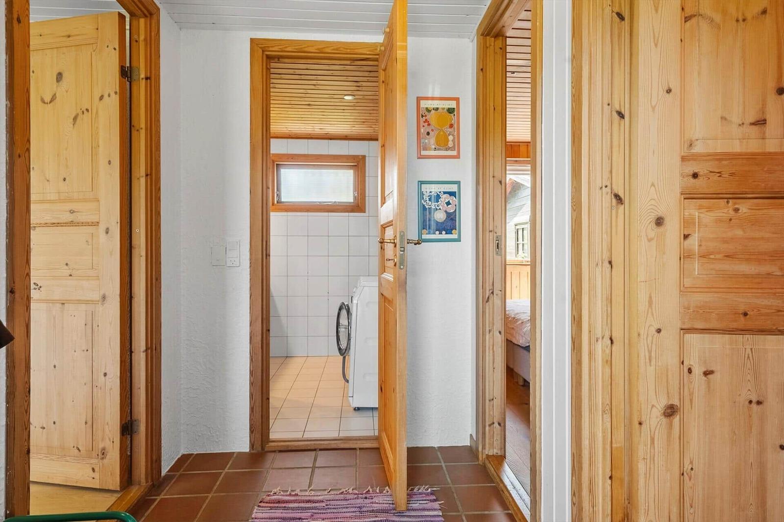 Flur mit Holztüren, Waschmaschine im angrenzenden Raum und Blick in Schlafzimmer.
