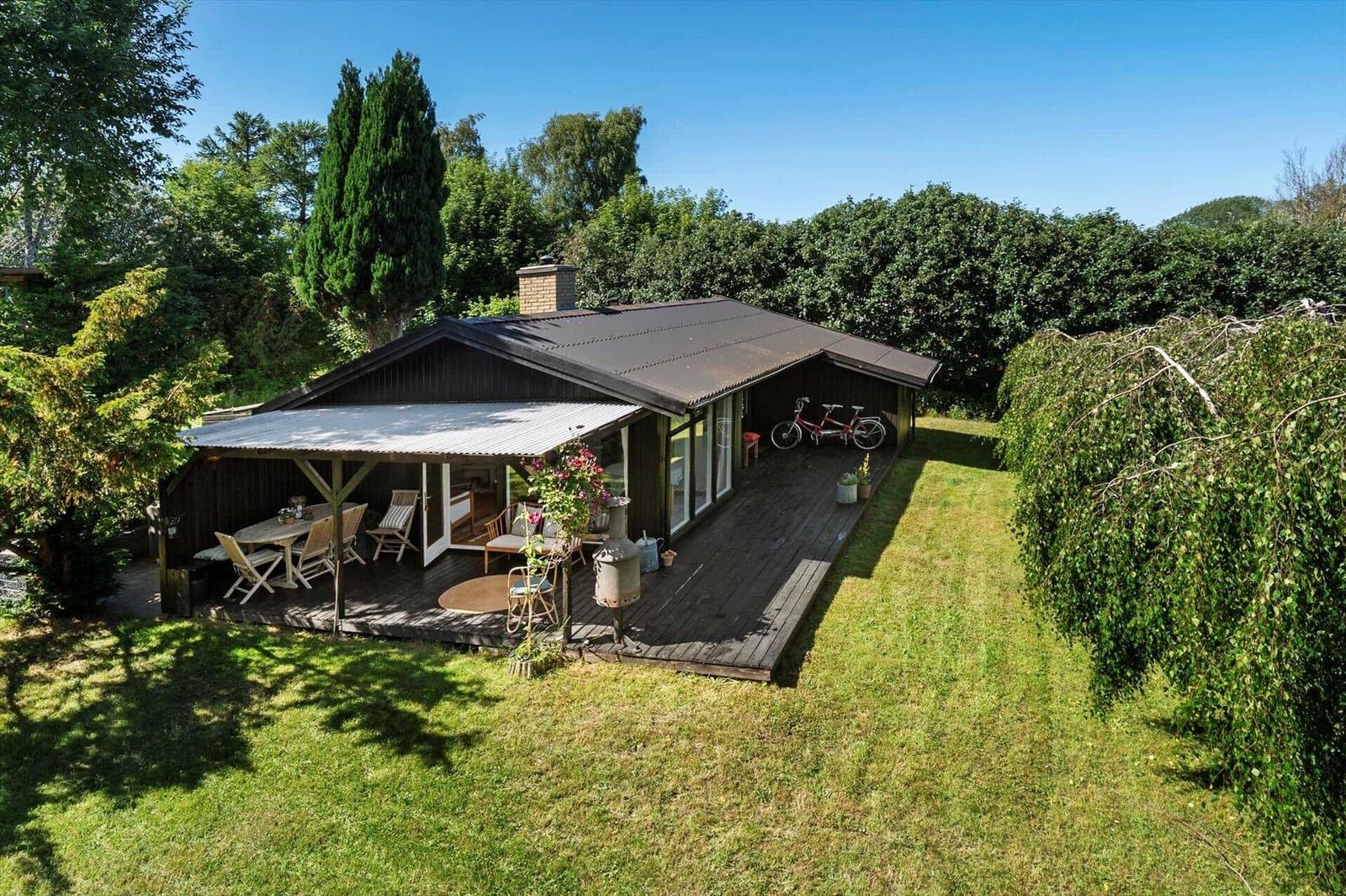 Haus mit Terrasse, Grill und Fahrrad im grünen Garten.