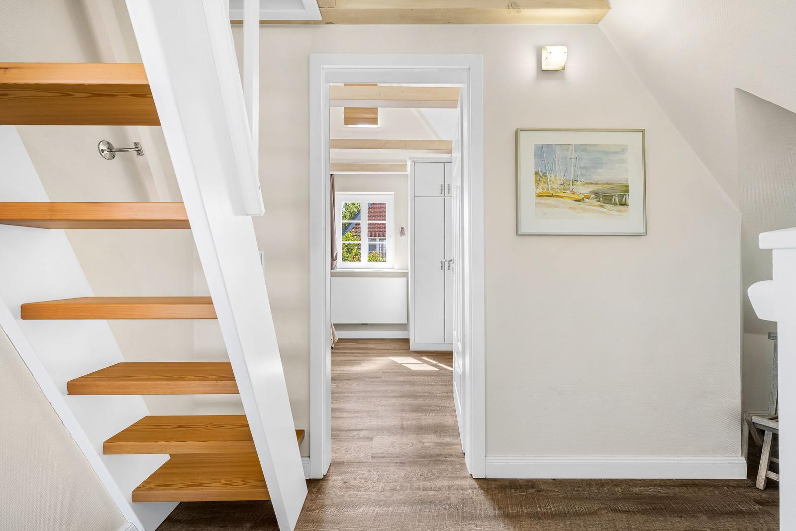 Staircase with wooden steps, wall art, and view into the bedroom.
