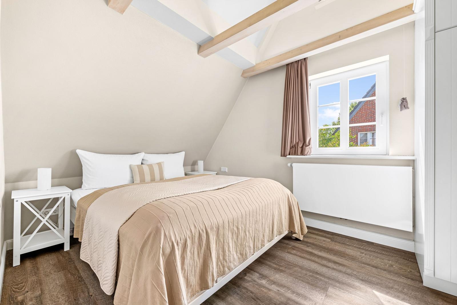 Bedroom with sloped ceiling, window, bed, and wooden floor.