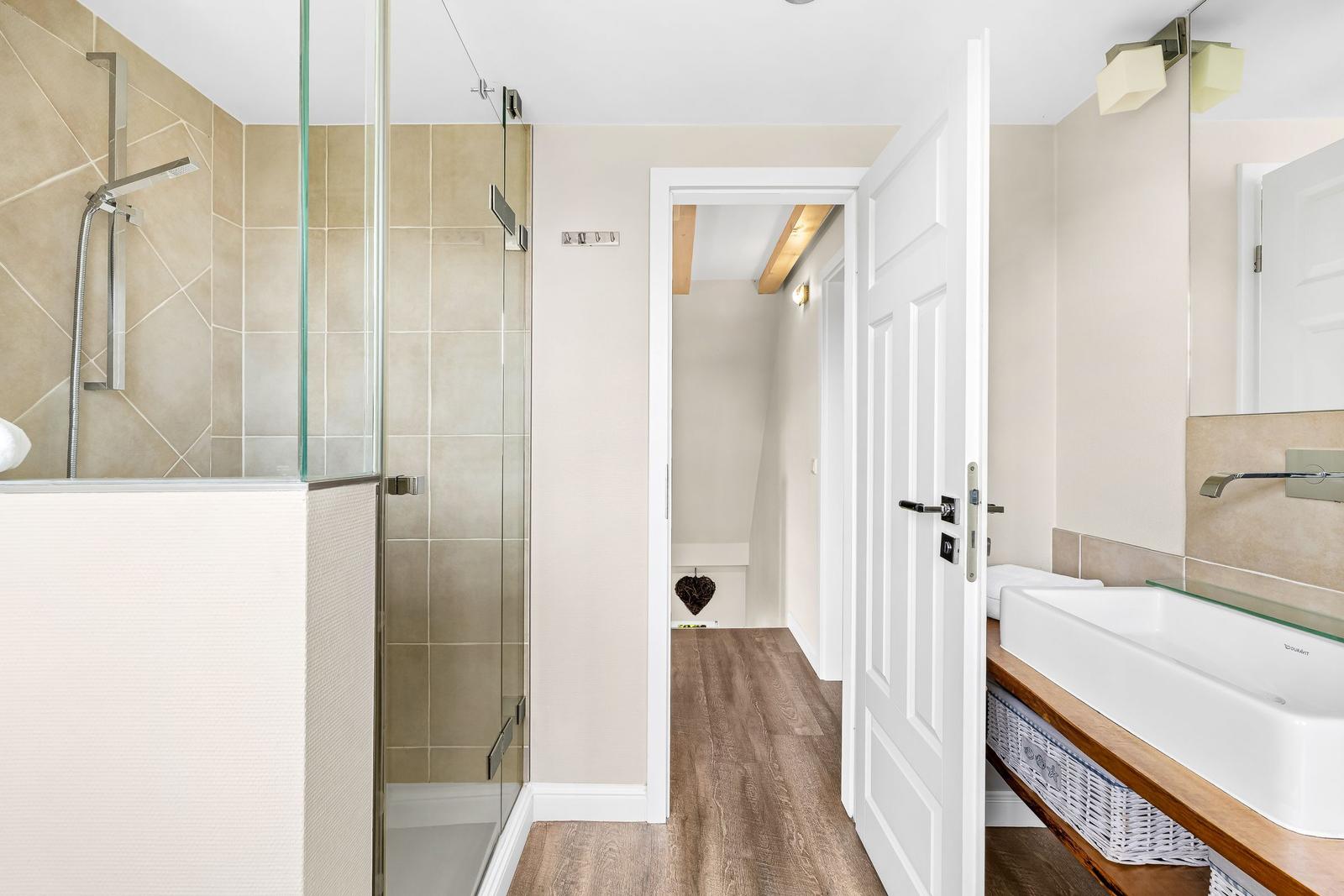 Bathroom with shower, sink, and view into the hallway.