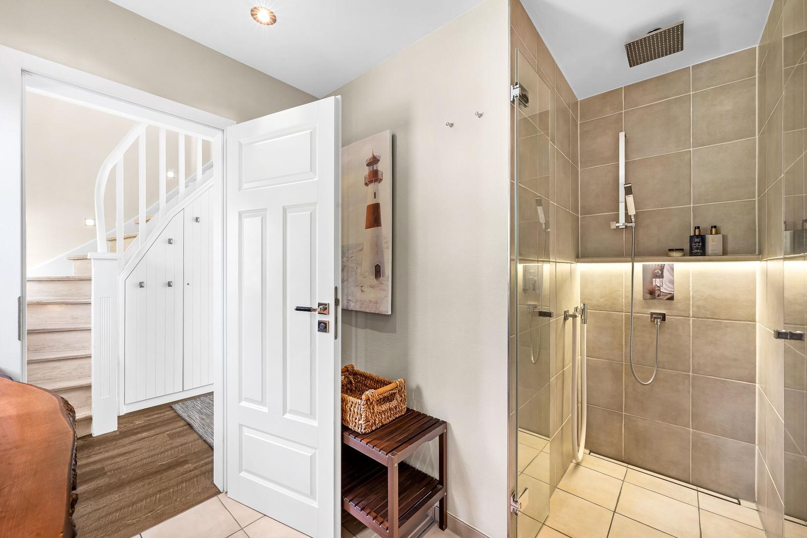 Hallway with shower and stairs to upper floor.