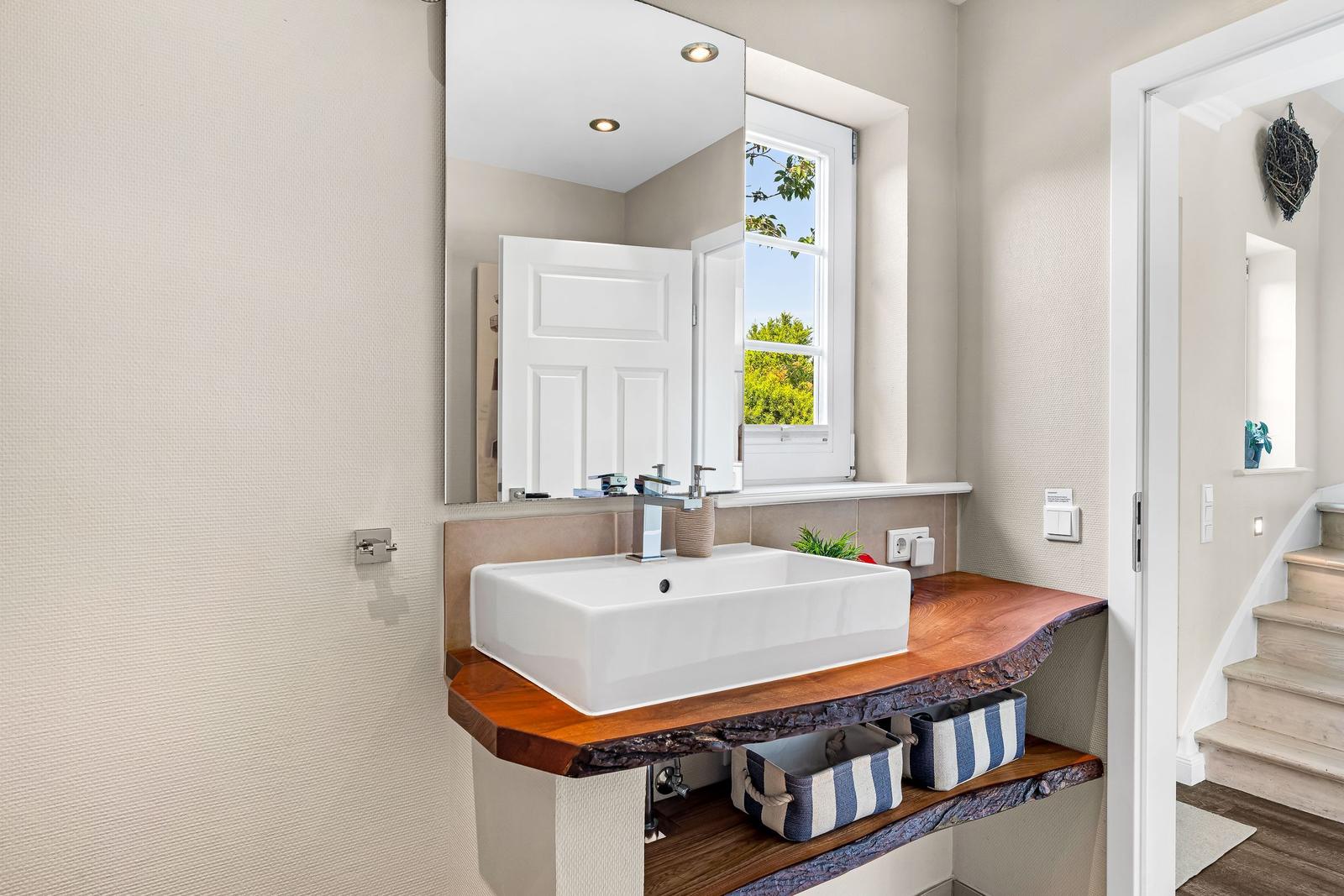 Sink with wooden vanity and mirror above the window