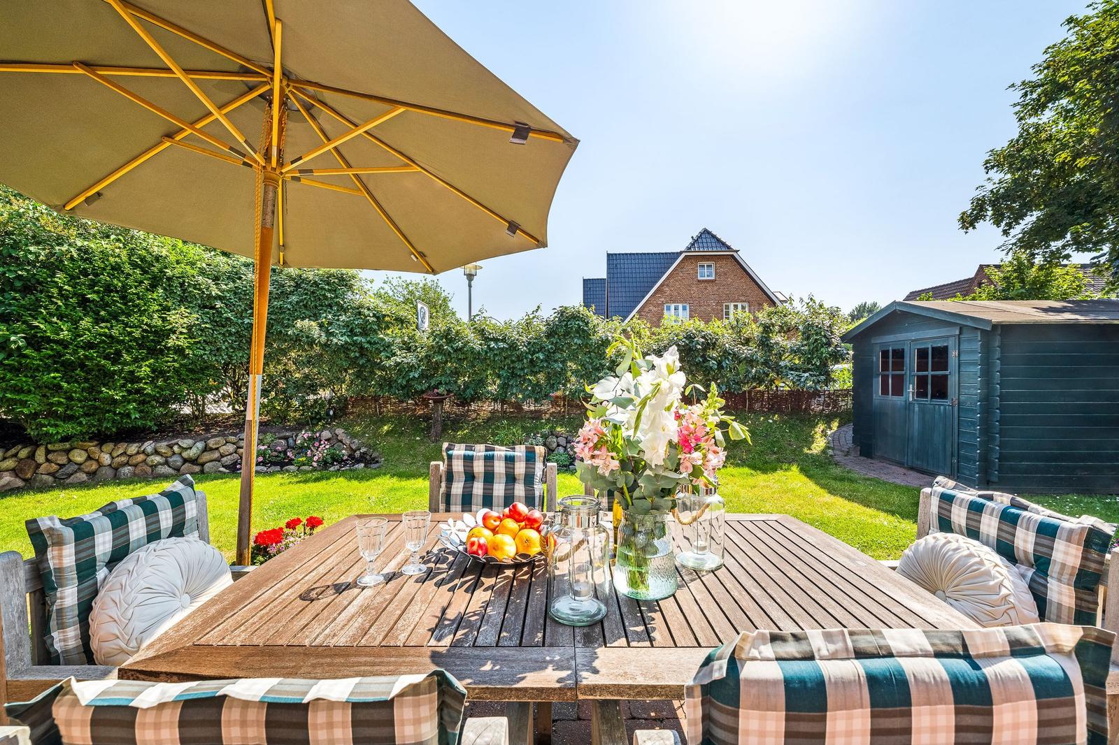 Wooden table with seating under an umbrella in the garden.