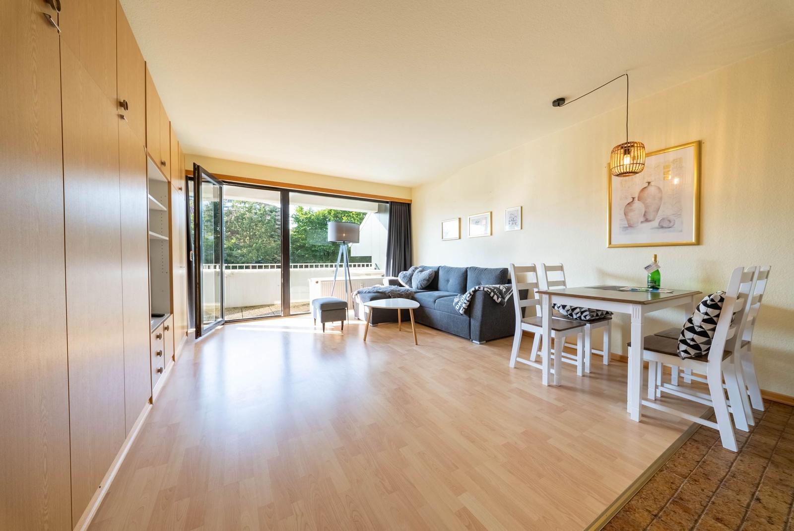 Wohn- und Essbereich mit Sofa, Tisch, Stühlen und Terrassentür.