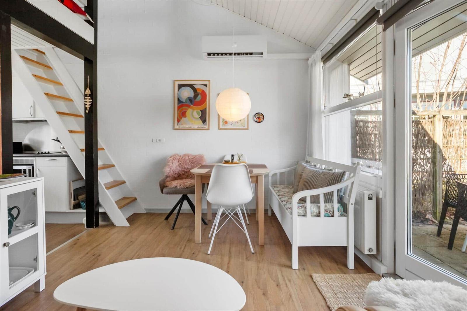 Wohnbereich mit Esstisch, Sofa und Treppenhaus zu Schlafzimmer.