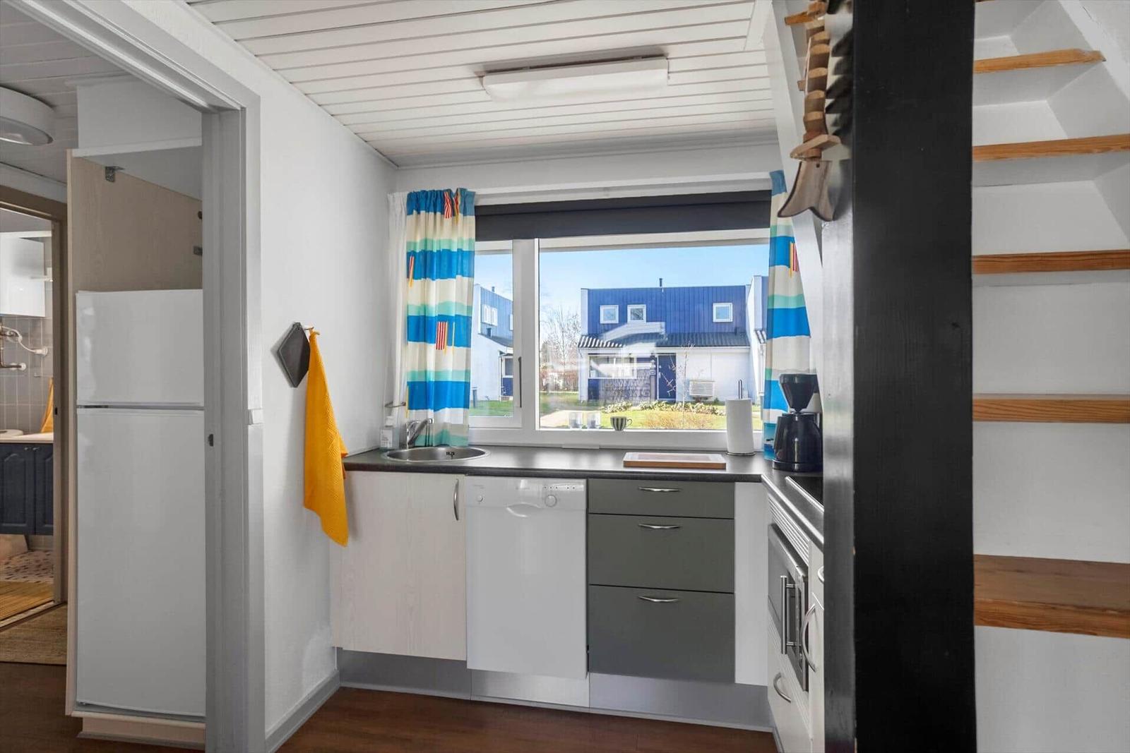 Küche mit Spüle, Waschmaschine und Fenster mit Blick auf Haus.
