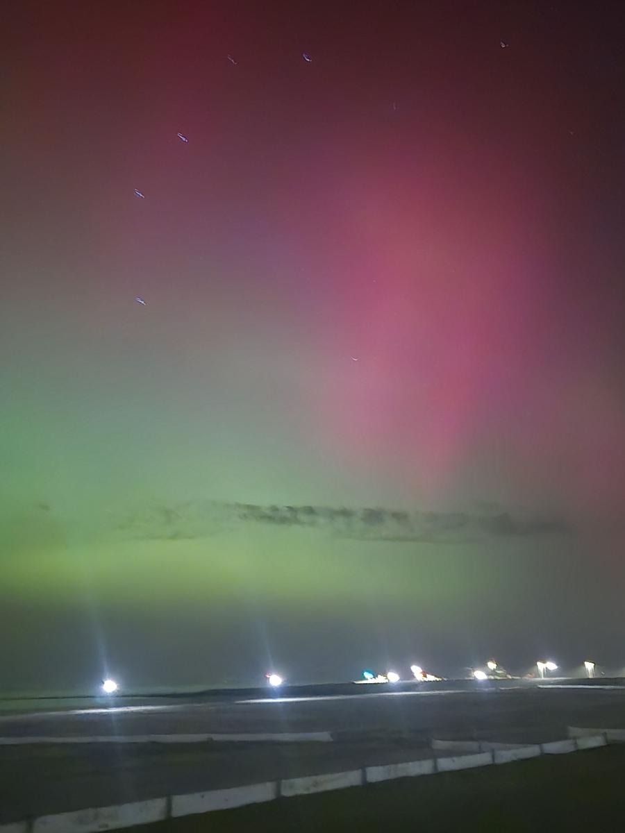 Nachtansicht eines Flughafens mit buntem Nordlicht am Himmel.