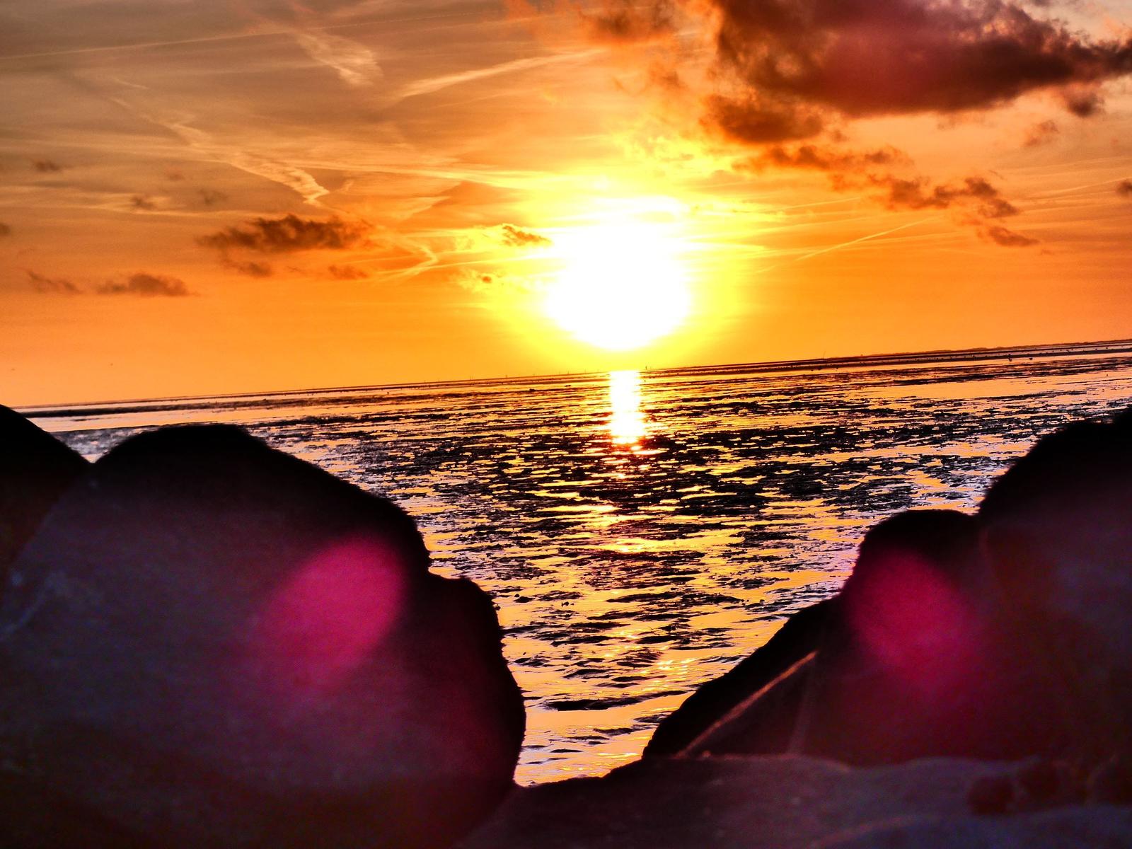 Sonnenuntergang über Meer mit Felsen im Vordergrund
