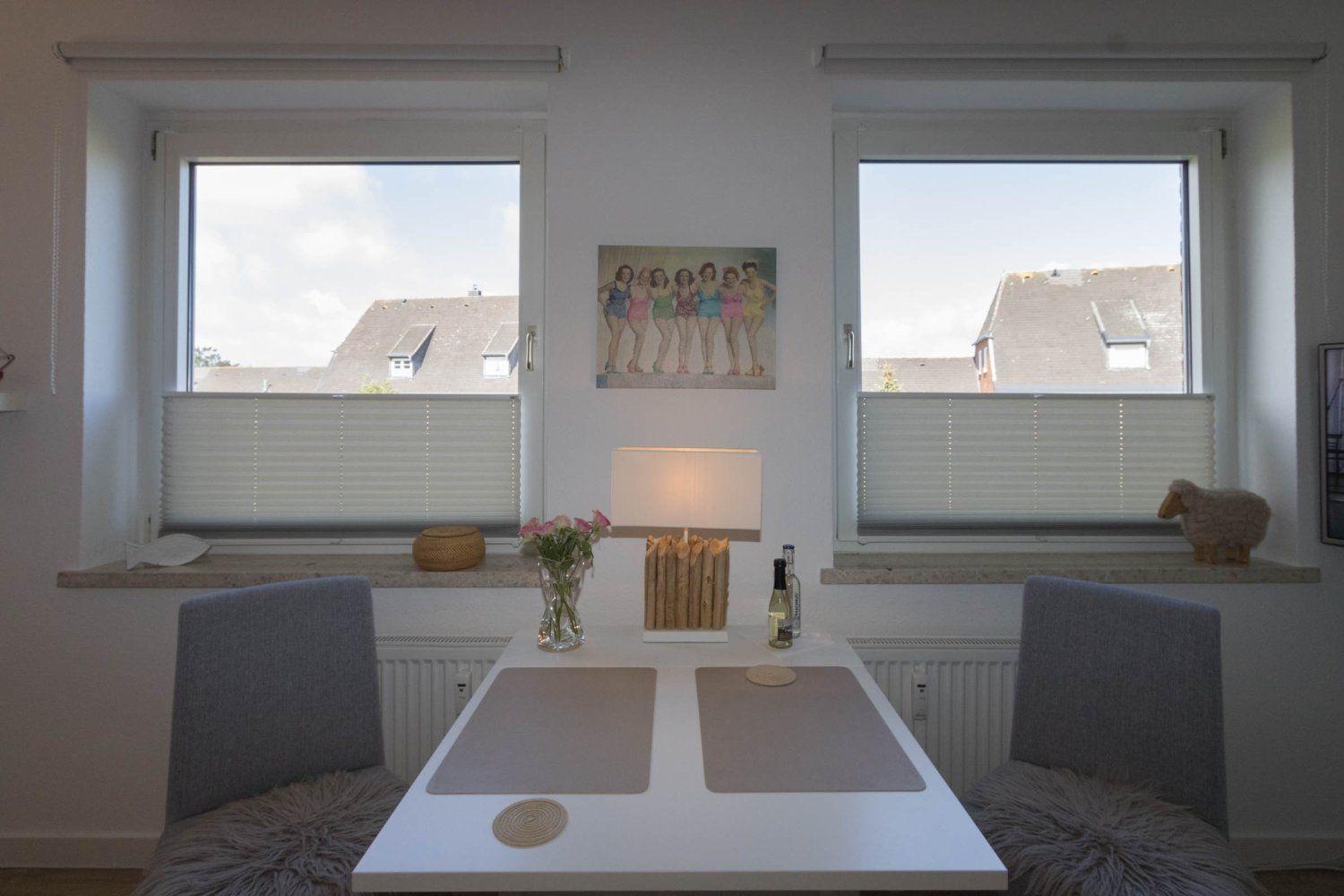 Dining area with table, two chairs, and windows with blinds.