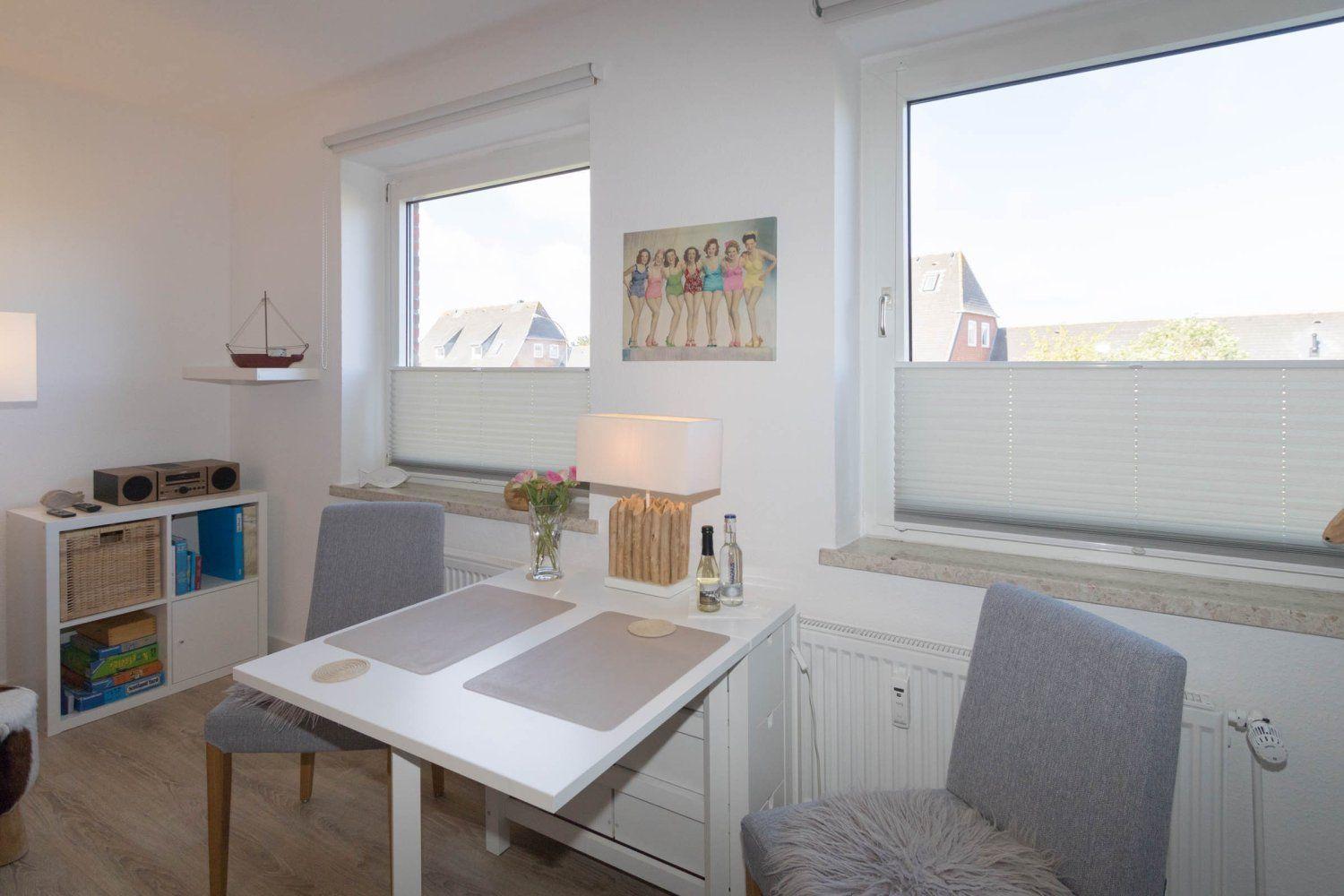 Dining area with table, two chairs, and view of rooftops.