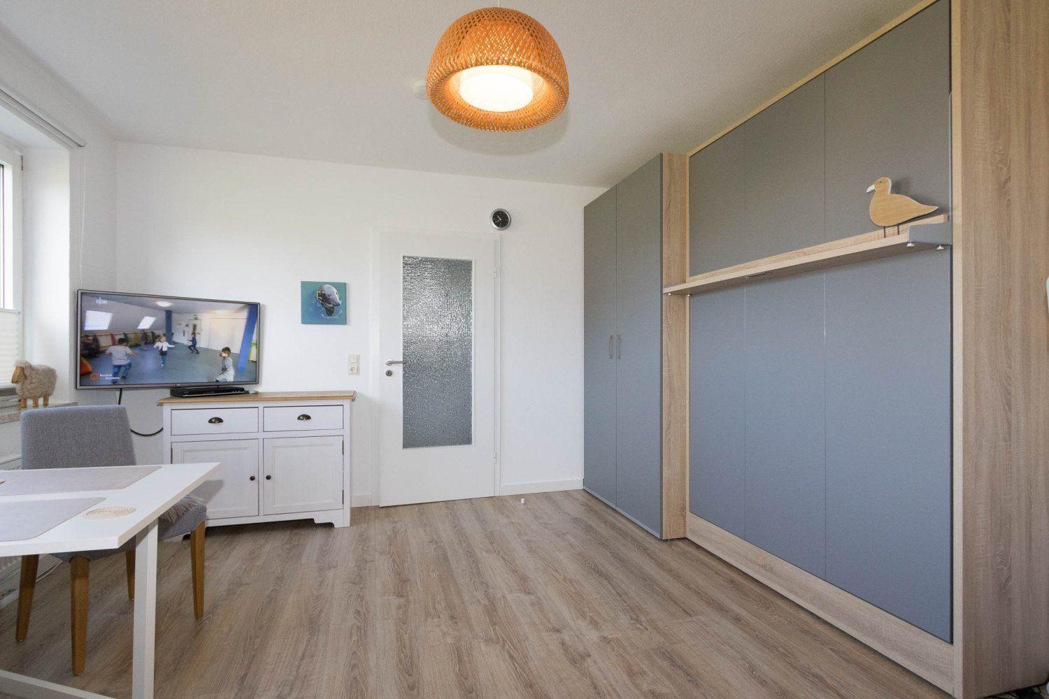 Living and dining area with TV, cabinets, and wooden floor.