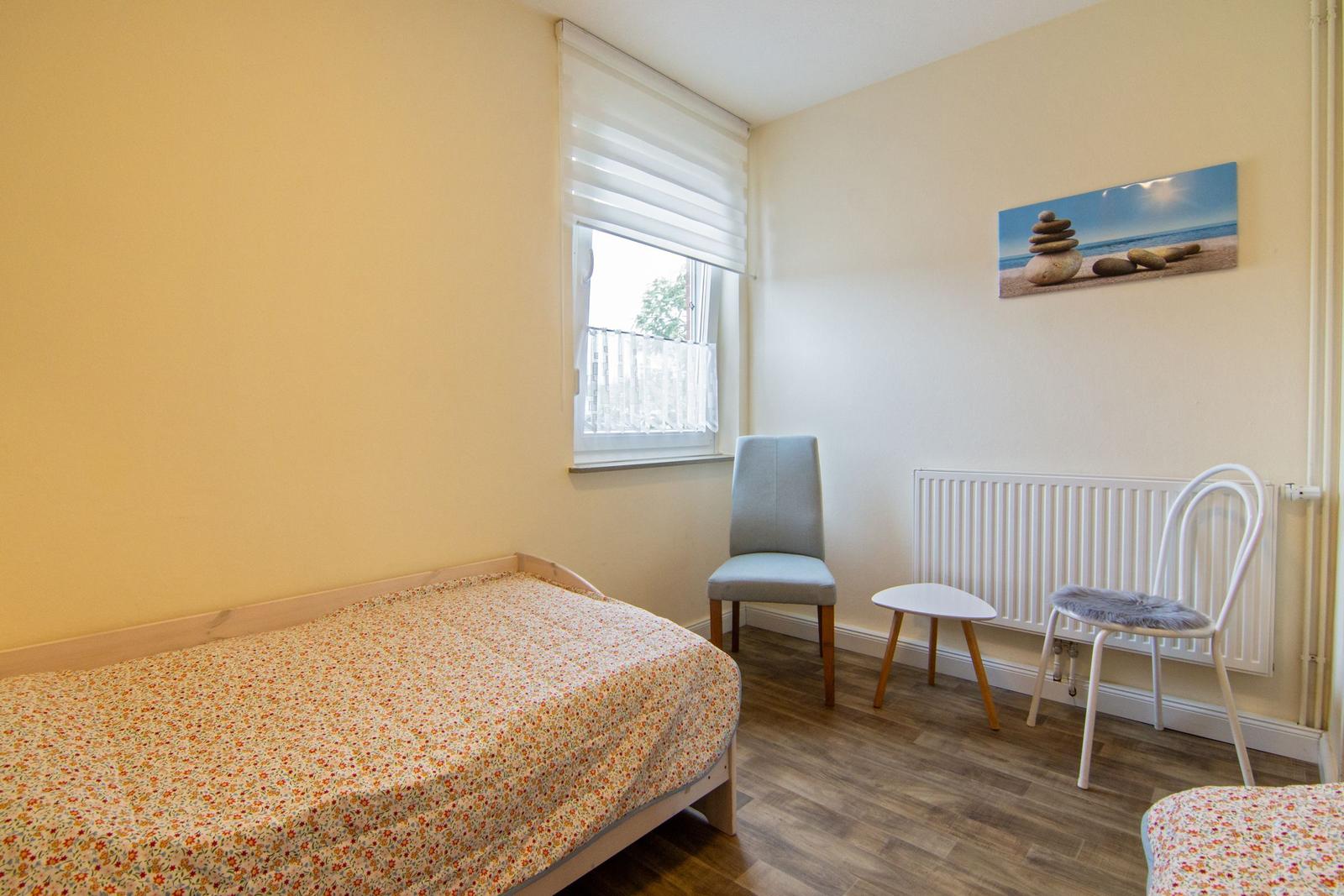 Ein Schlafzimmer mit Bett, Stuhl und Bild an der Wand.
