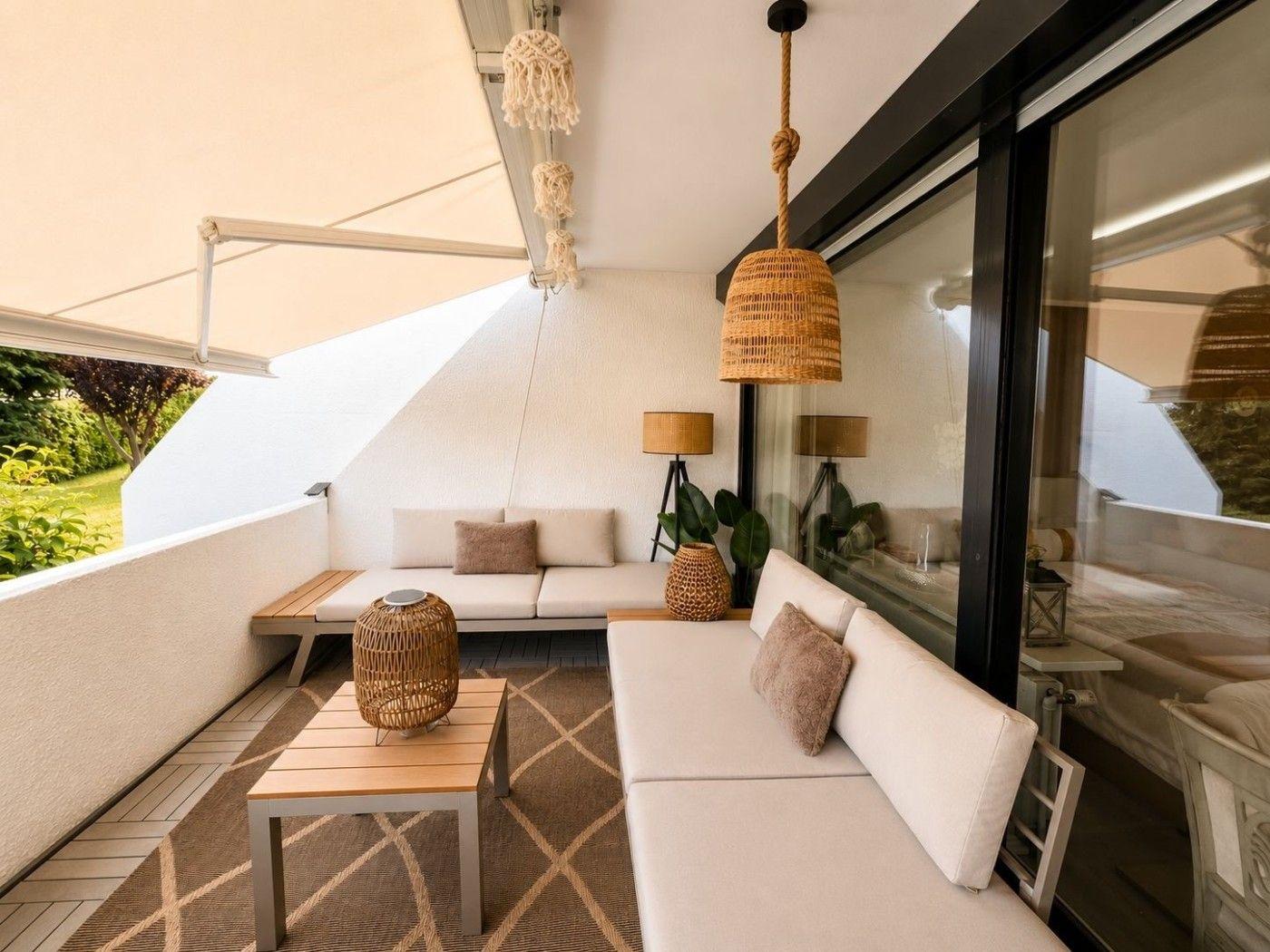 Terrasse mit Sitzgelegenheiten, Sonnenschutz und Hängelampe.