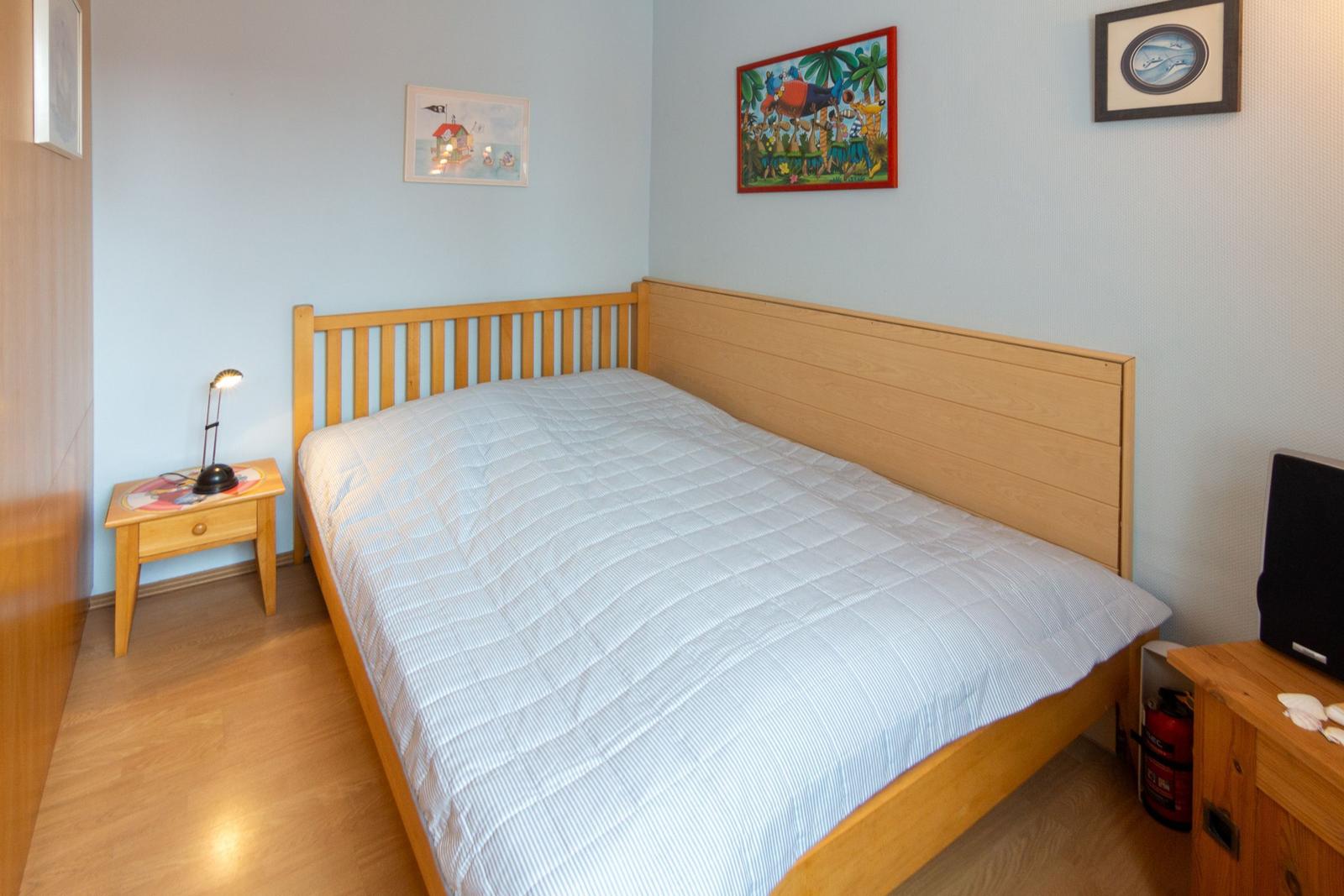 Schlafzimmer mit Holzbett, Nachttisch und Wandbildern