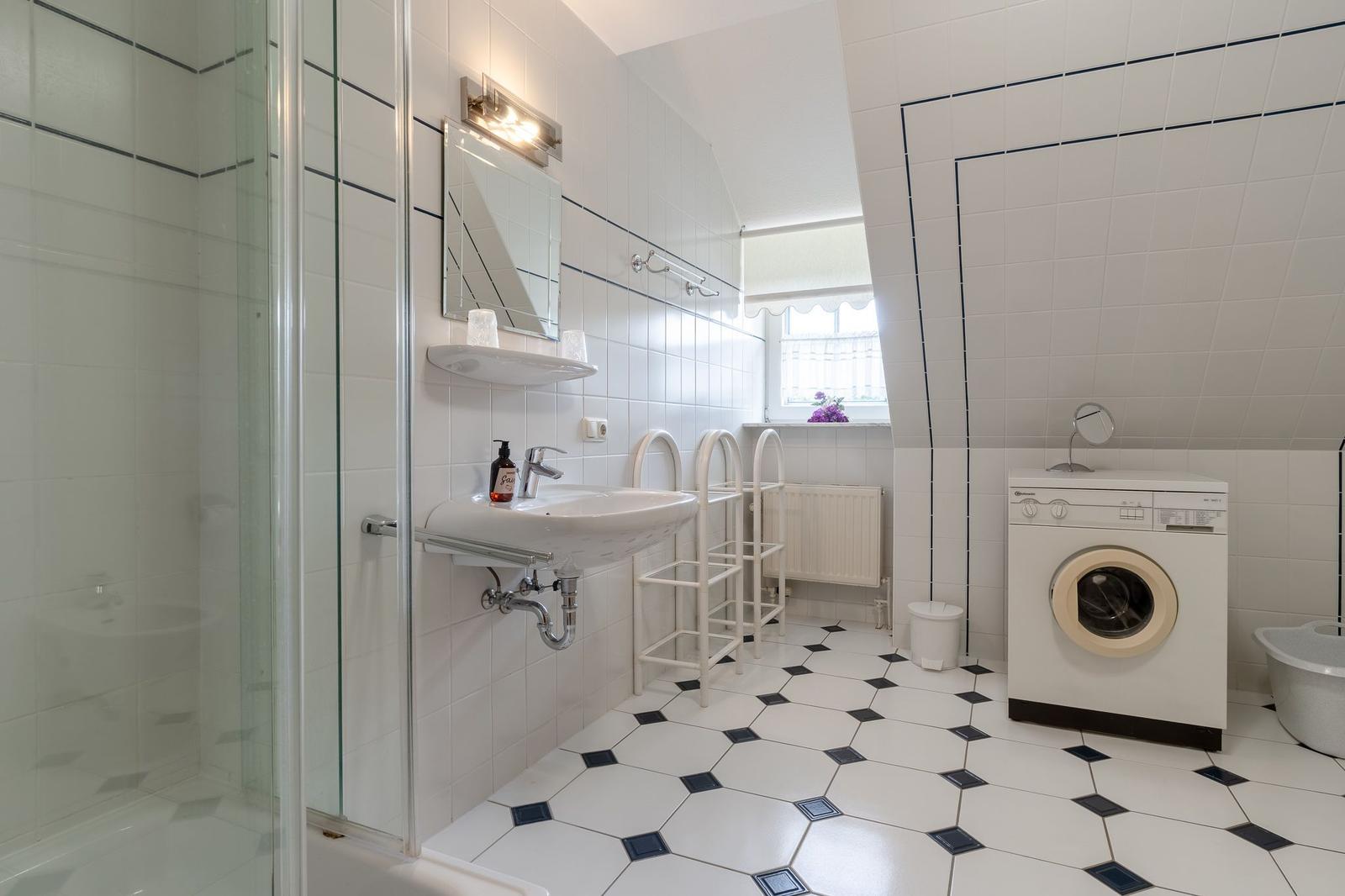 Badezimmer mit Dusche, Waschbecken, Waschmaschine und Fenster