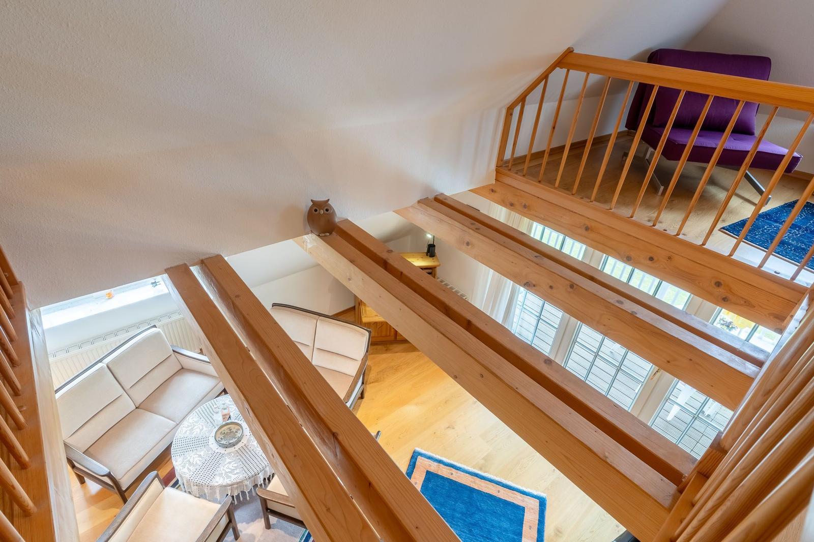 Holzgetäfelte Treppe führt zu einer Galerie mit lila Sitzgelegenheit.