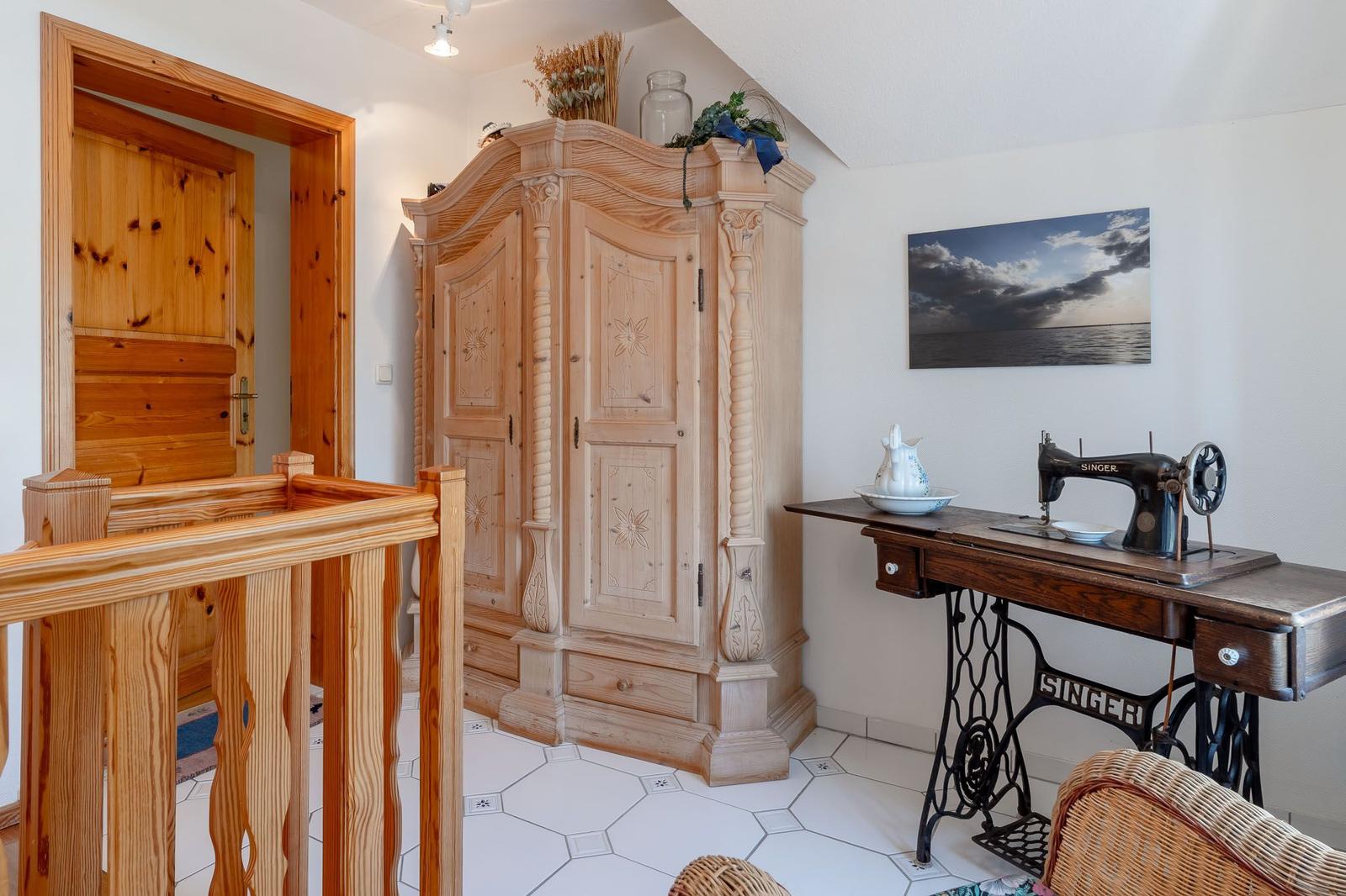 Holzgetäfeltes Schlafzimmer mit Schrank, Nähmaschine und Wandbild.