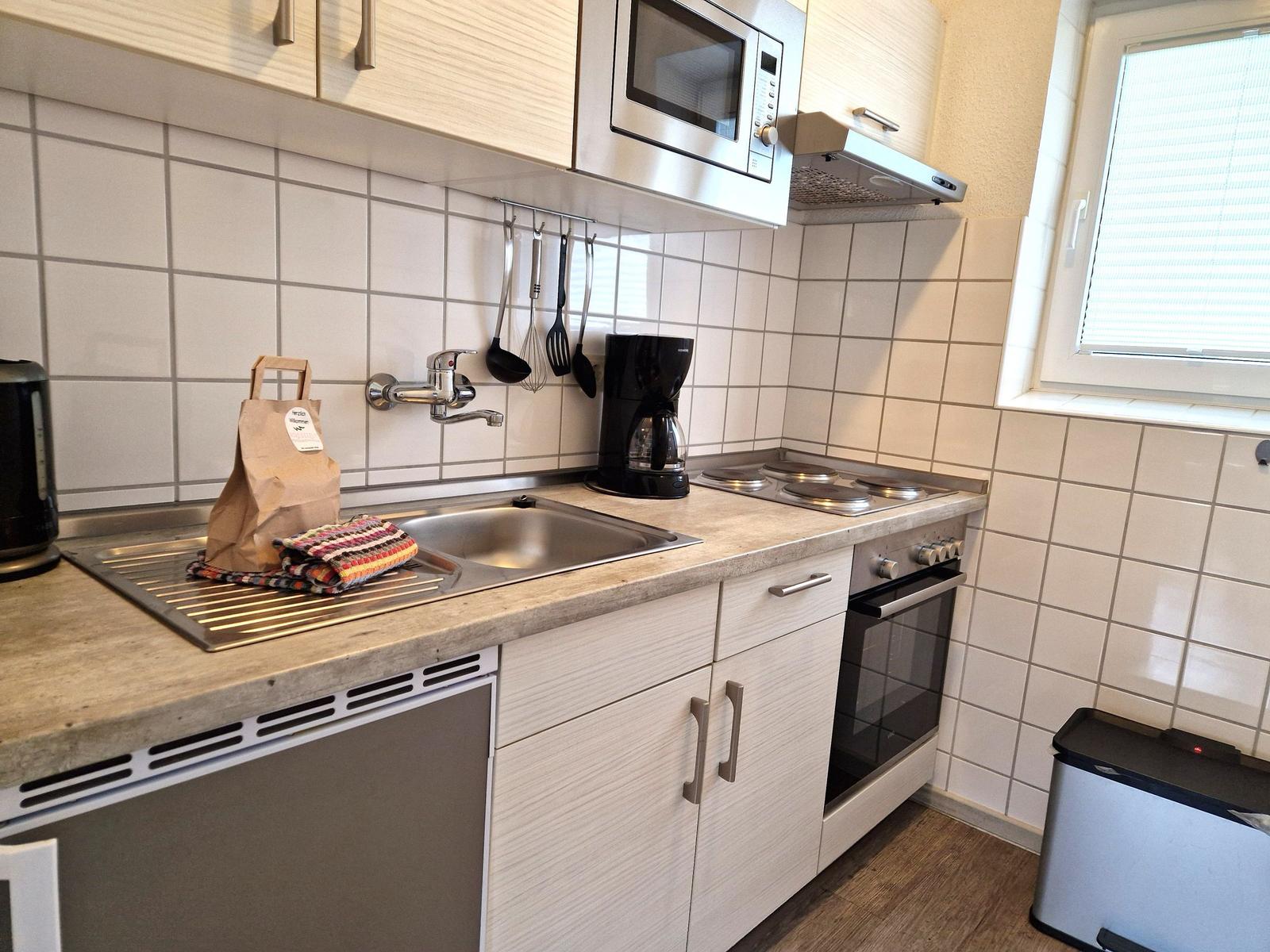 Küche mit Spüle, Herd, Mikrowelle und Fenster