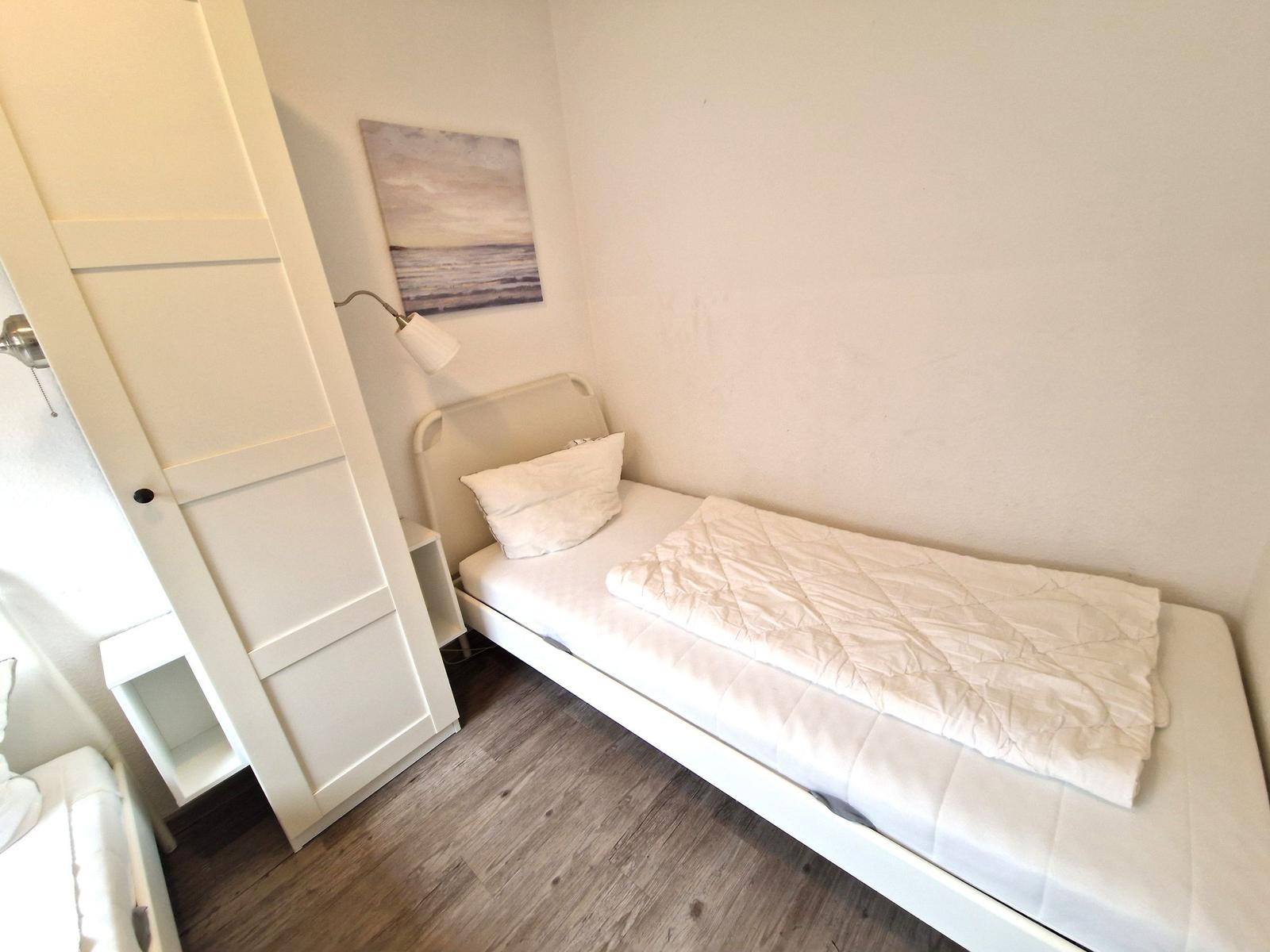 Ein Schlafzimmer mit einem Bett, einer Wandlampe und einem Bild an der Wand.