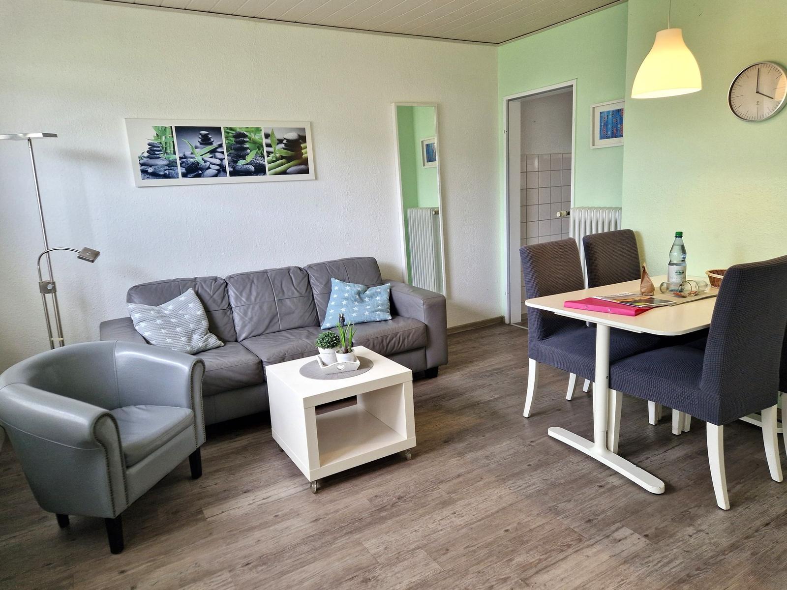 Wohn- und Essbereich mit Sofa, Sessel, Tisch und Stühlen.
