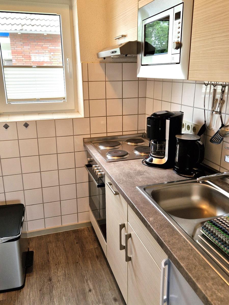 Küche mit Kochfeld, Spüle, Mikrowelle und Kaffeemaschine.