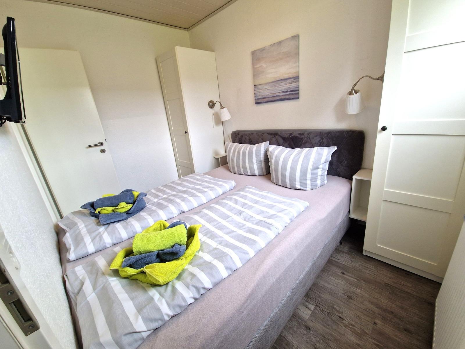 Schlafzimmer mit Doppelbett, Wandlampen und Bild an der Wand.