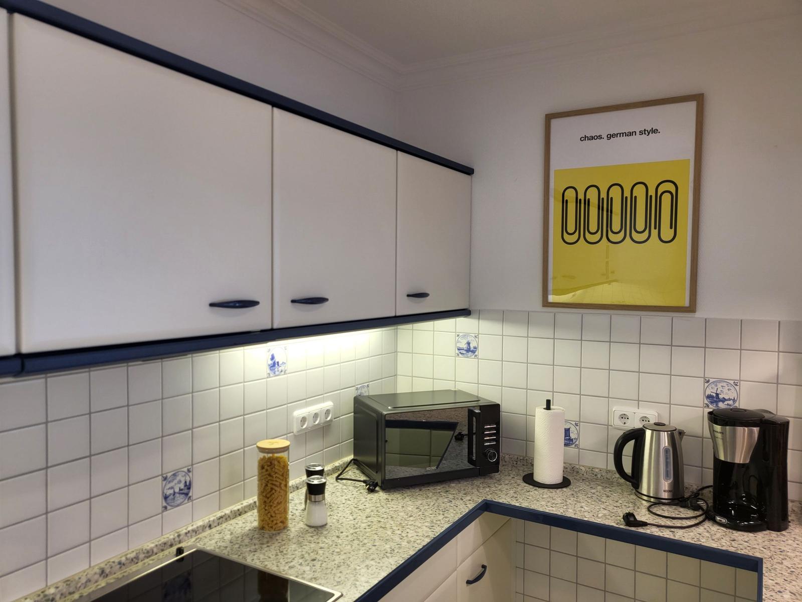 Küche mit weißen Schränken, Mosaikfliesen und Küchengeräten.