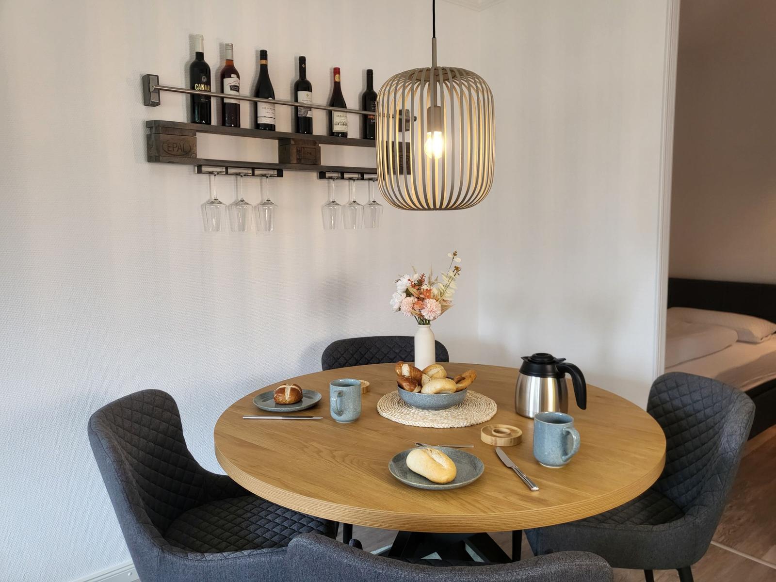 Rundes Esszimmer mit Tisch, Stühlen und Weinregal an der Wand.