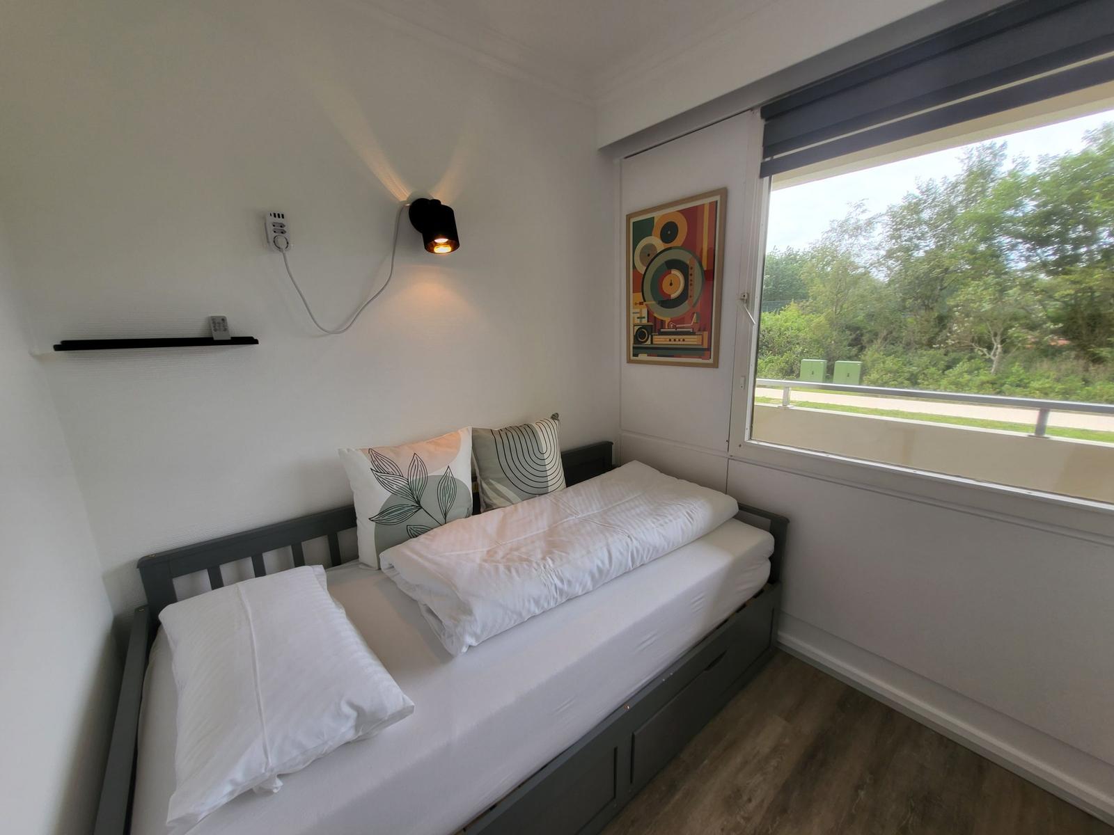 Schlafzimmer mit Bett, Fenster und Wandbild.