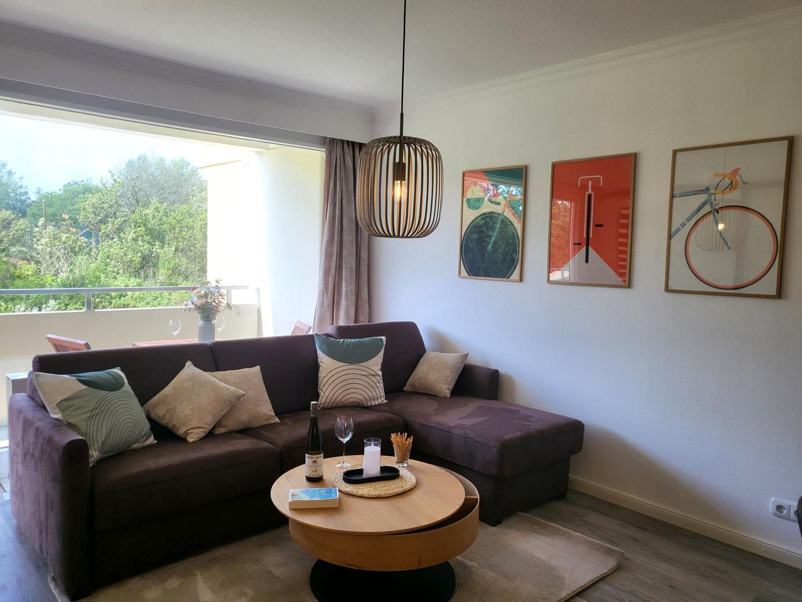 Ein Wohnzimmer mit braunem Sofa, runden Tisch und Wandbildern.