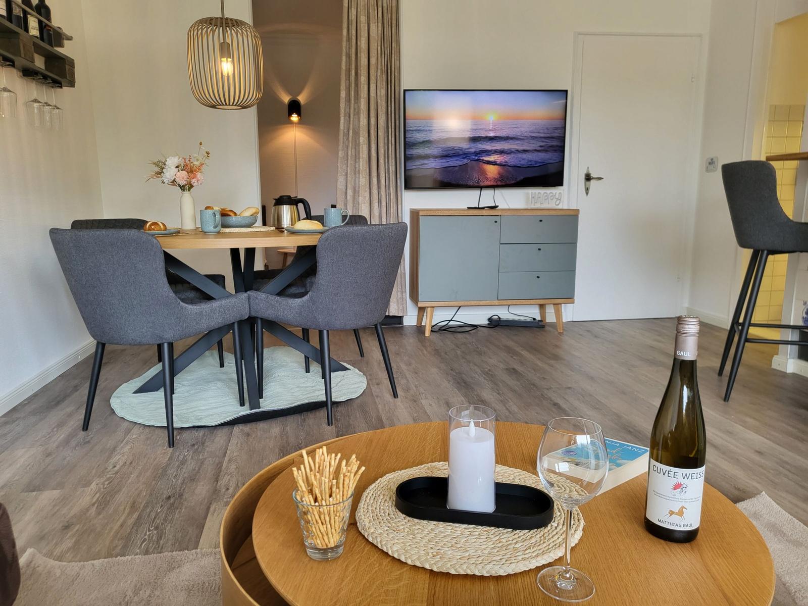 Essbereich mit Tisch und Stühlen. Fernseher auf Schrank. Tisch mit Kerze und Wein.