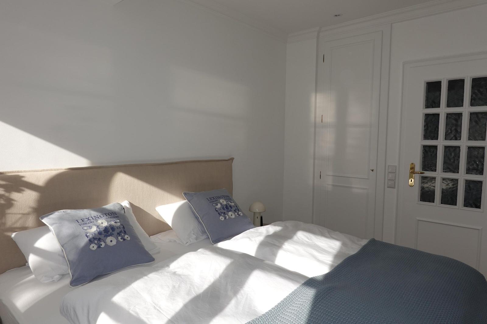Schlafzimmer mit Bett, Kissen und Tür mit Glasfenstern.