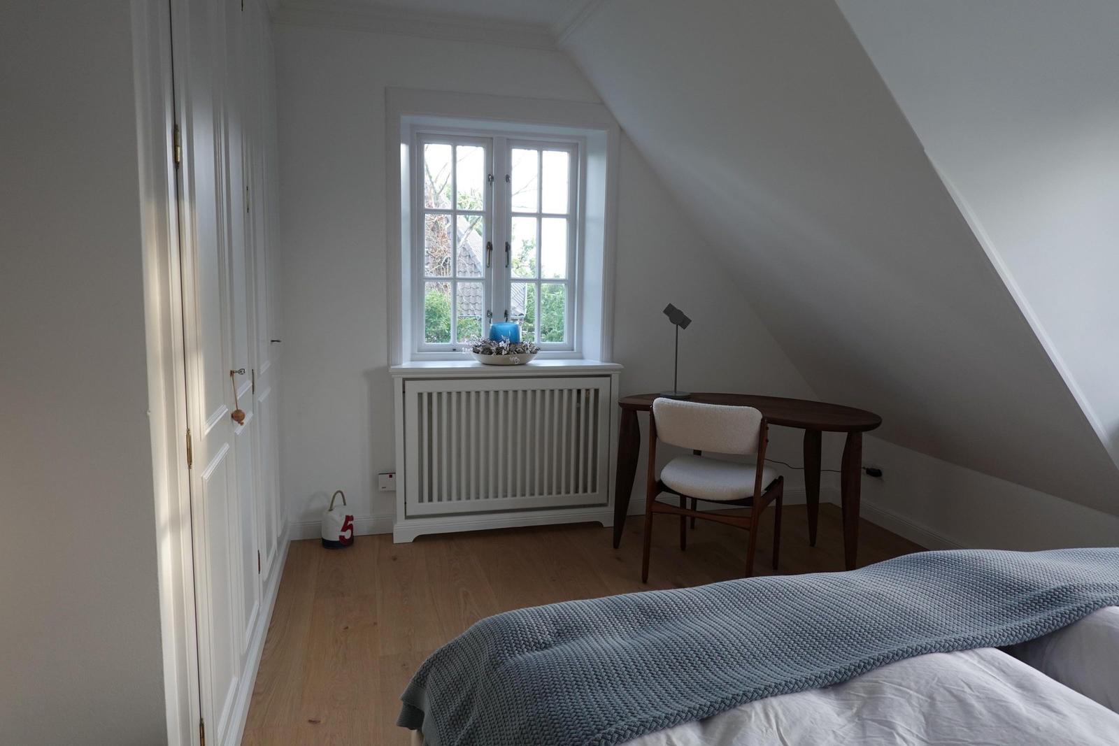 Schlafzimmer mit Dachschräge, Fenster, Schreibtisch und Bett