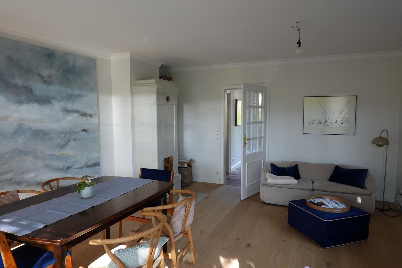 Esszimmer mit Tisch und Stühlen. Wohnbereich mit Sofa und Kissen.