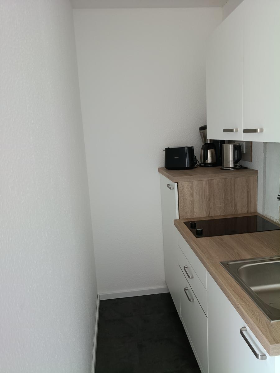 Küche mit Holzwerkstoffplatte, Spüle, Herd und Küchengeräten.