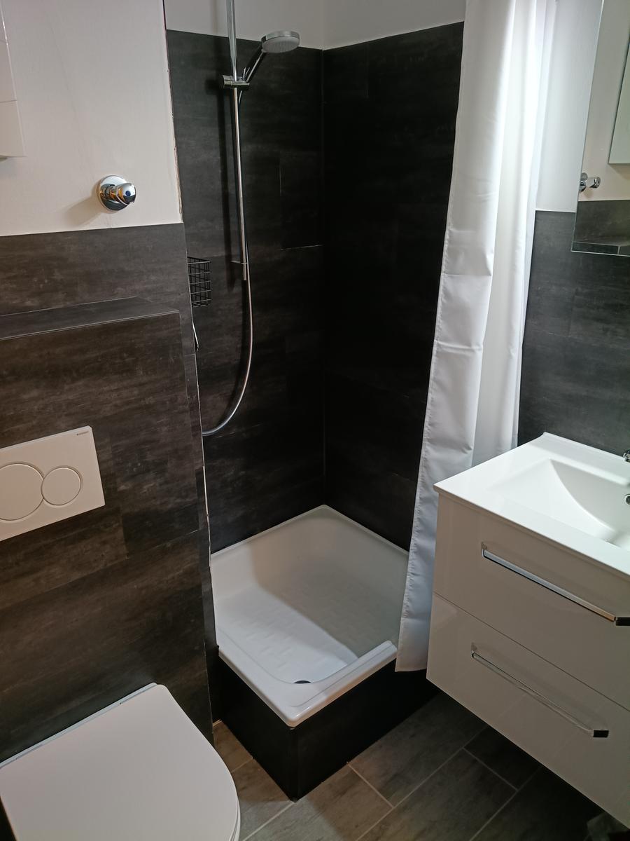 Badezimmer mit Dusche, Waschbecken und WC.
