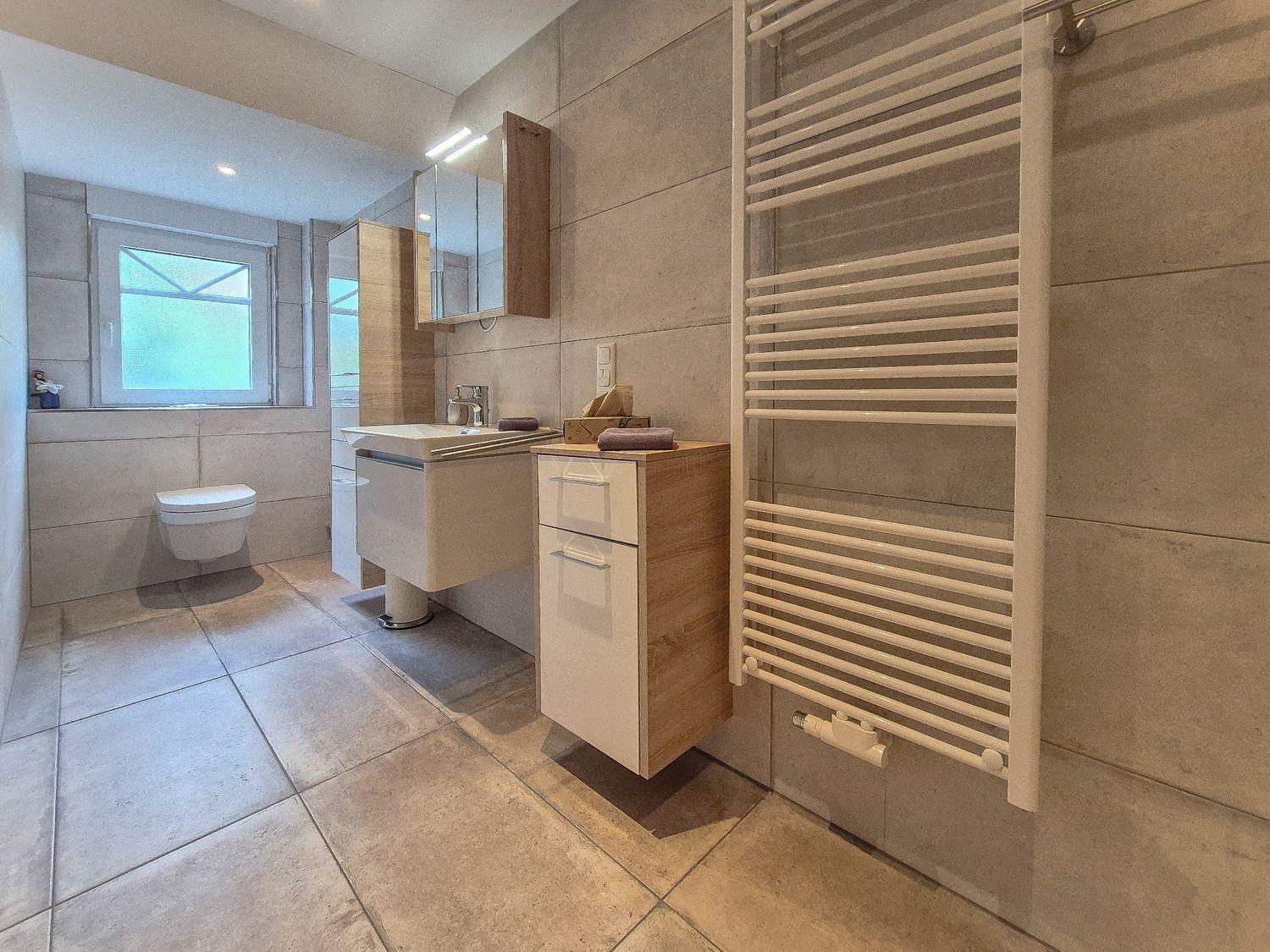 Badezimmer mit Toilette, Waschbecken und Heizkörper an der Wand.