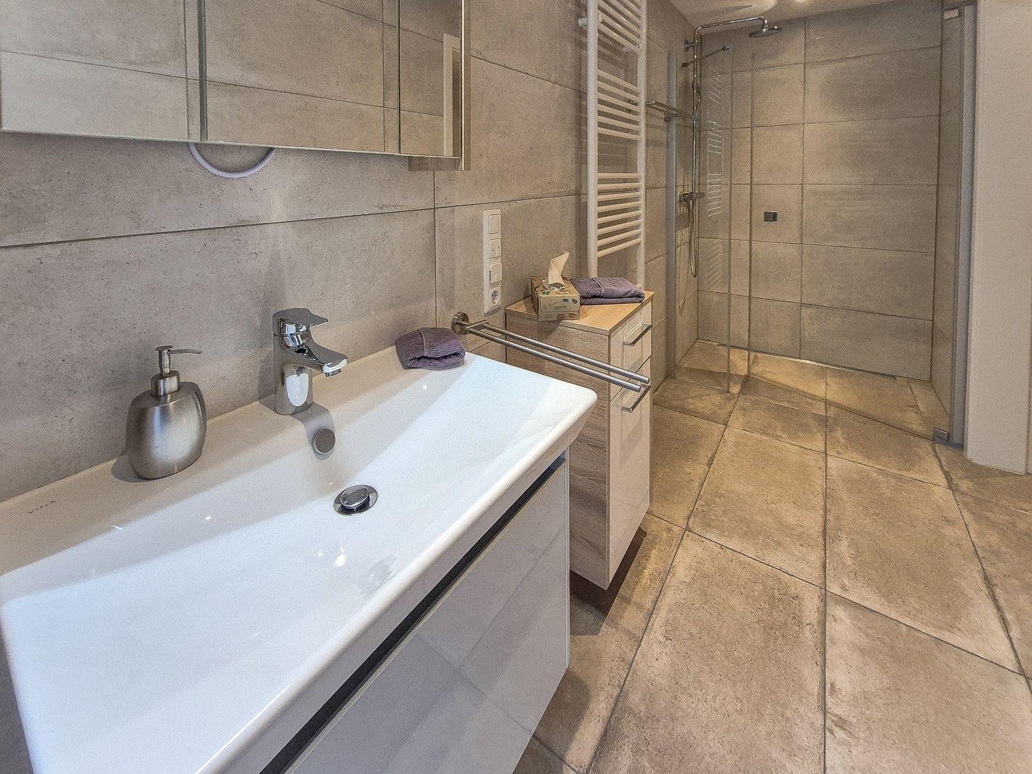Bad mit Dusche, Waschbecken und Handtuchhalter.