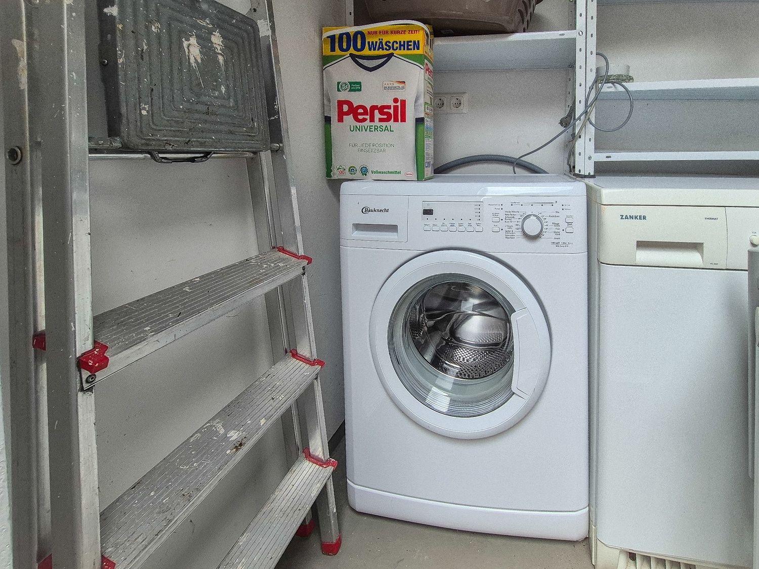 Waschmaschine und Spülmaschine in einem Raum mit Leiter und Waschmittel.