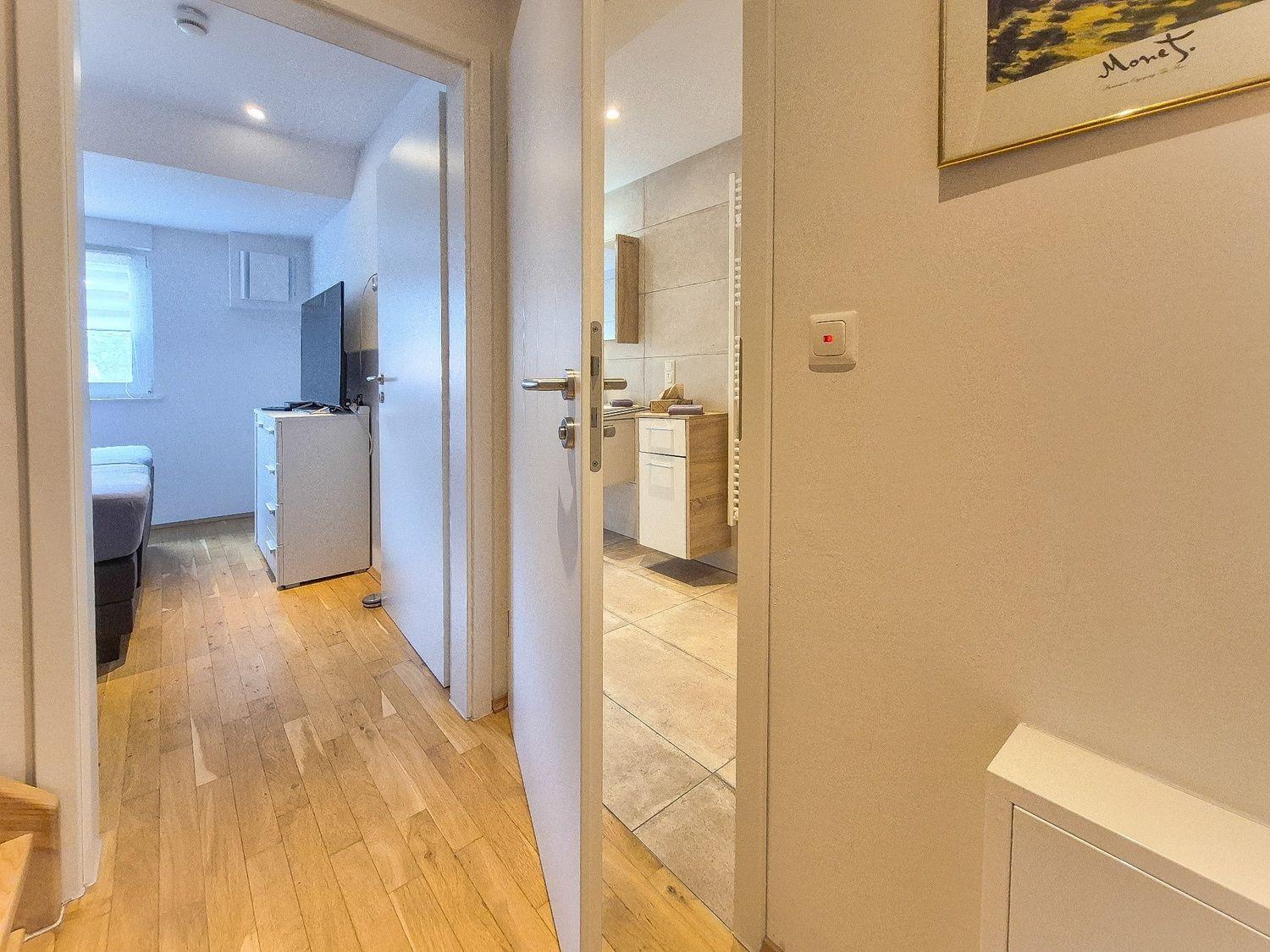 Flur mit Blick in Schlafzimmer und Bad. Holzfußboden und moderne Einrichtung.